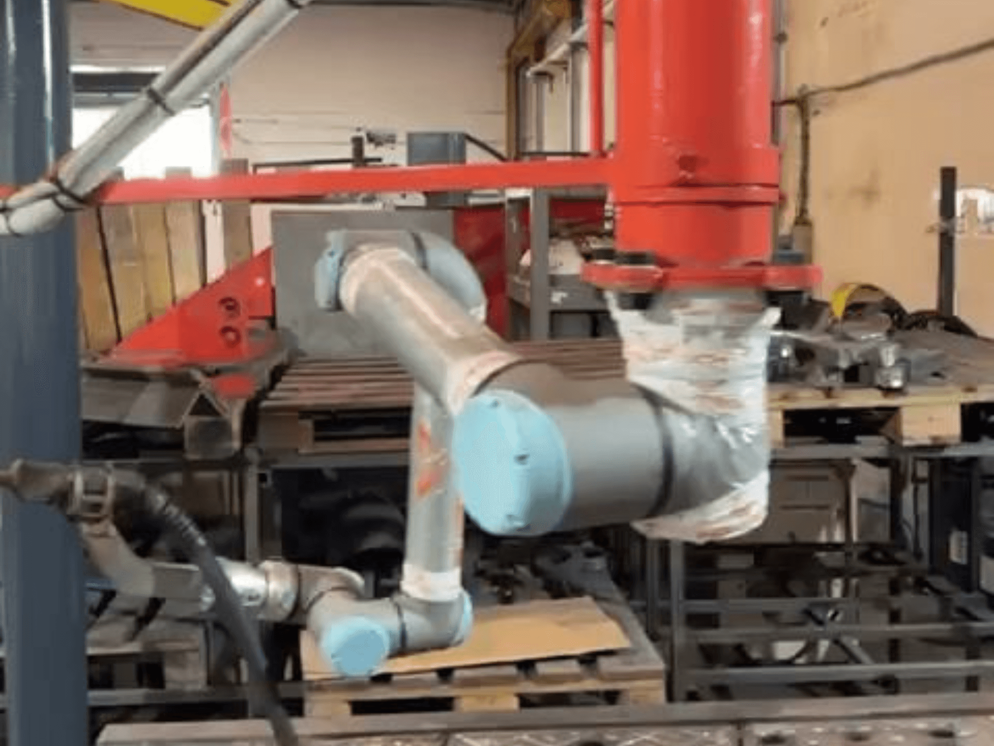 Kollaborativer Roboter UR10e von Universal Robots in einer Werkstatt; Seitenansicht, die die Bewegungen des Arms und der Gelenke in der Nähe von Maschinen zeigt.