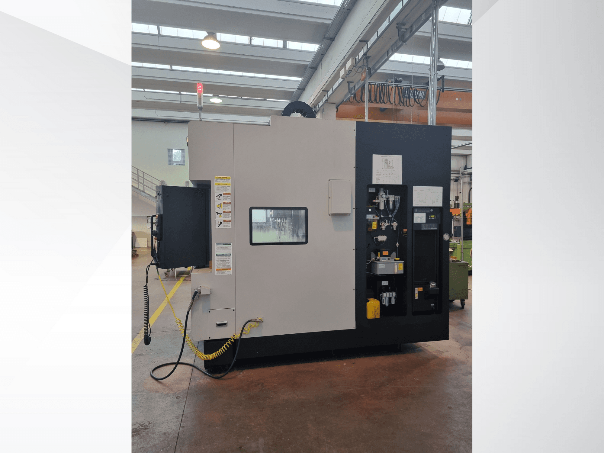 Industriemaschine in der Seitenansicht, mit einem Bedienfeld mit Tasten, Anzeigen und einem Sicherheitswarnschild.