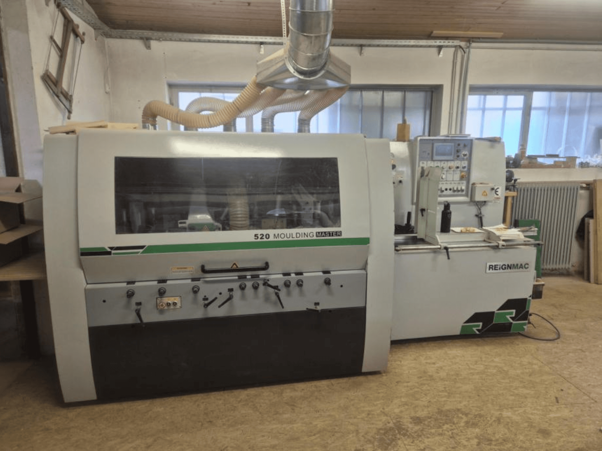 Vorderansicht der REIGNMAC 520 MOULDING MASTER Hobelmaschine mit Bedienfeld, Vorschubwalzen und Staubabsaugsystem.