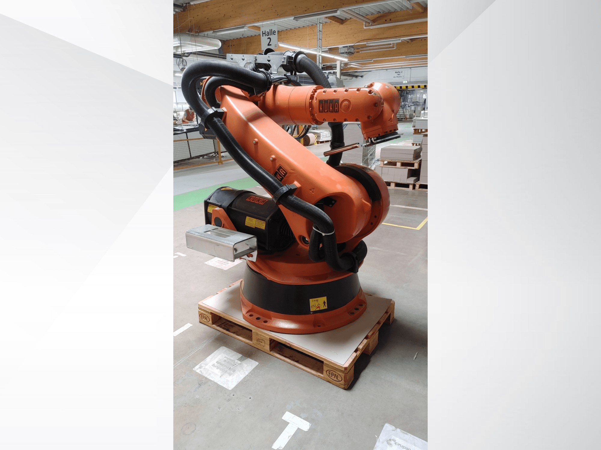 KUKA KR140-3 COMP Roboterarm in orange, Vorderansicht auf einer Holzpalette, mit gebogenem Arm und Steuerbox.