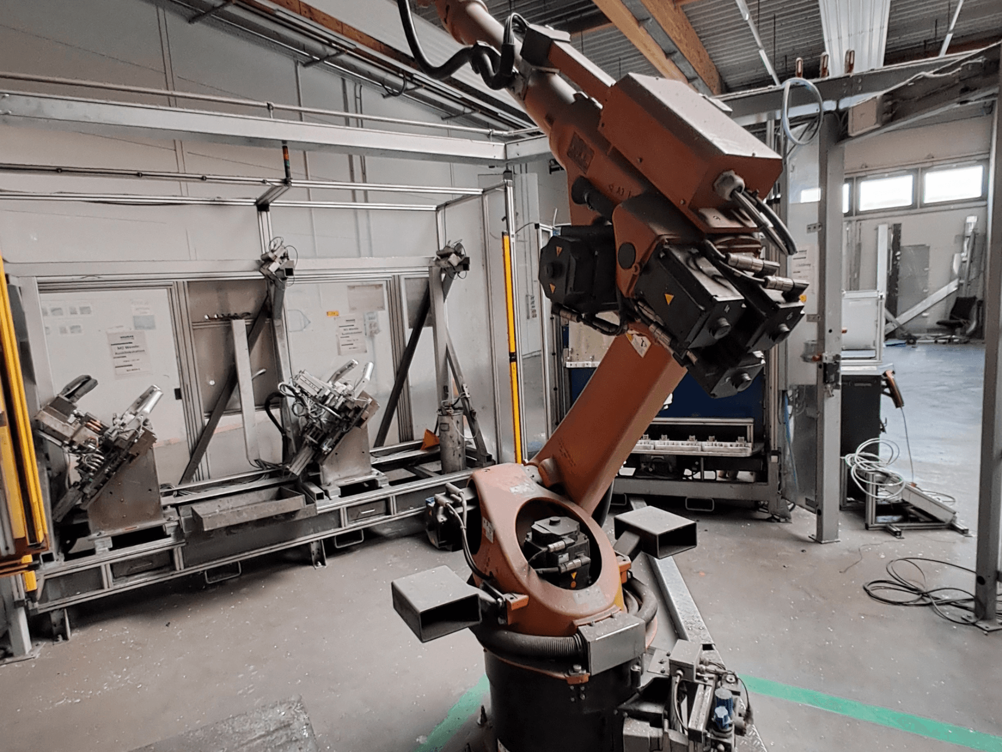 KUKA KR 30L16-2-Roboterarm in einer industriellen Umgebung, Seitenansicht, die die Gelenke und Greifwerkzeuge des Arms zeigt.