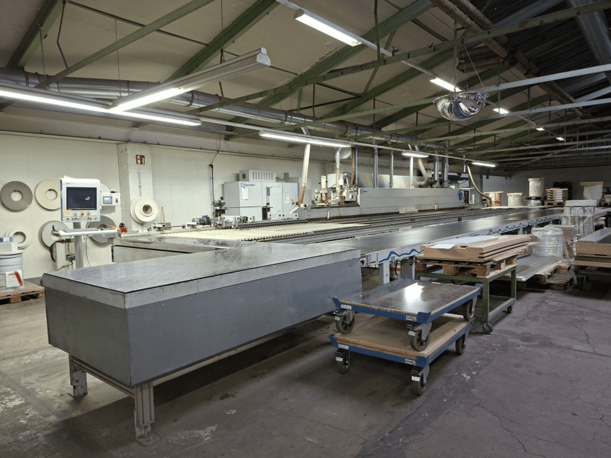 HOMAG Optimat KAL 330 Kantenanleimmaschine in der Seitenansicht mit langem Transporttisch und Bedienpult in einer Werkstatt.
