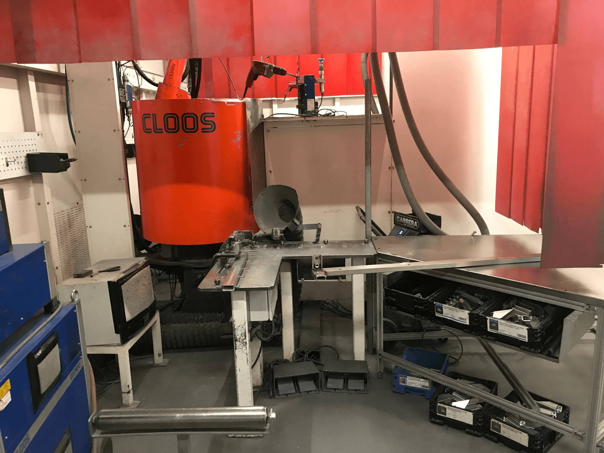 Schweißwerkstatt-System von DESSAUER, Vorderansicht mit Roboterarm, Metallbearbeitungsfläche und Lagerbereichen in einer Werkstattumgebung.
