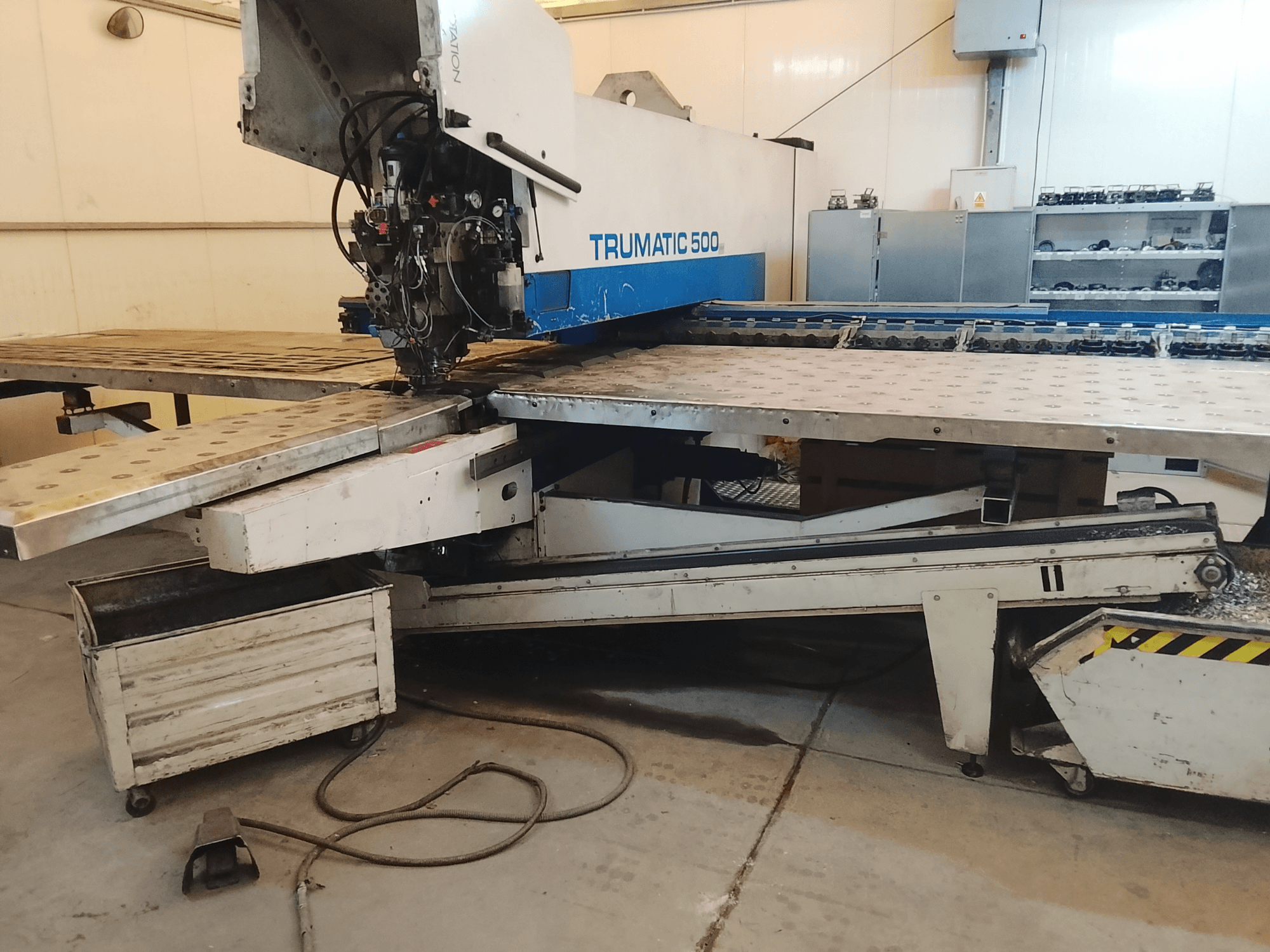 TRUMATIC 500 CNC-Maschine in einer Werkstatt, Seitenansicht mit Schneidkopf und Metallarbeitstisch mit vorgebohrten Löchern.