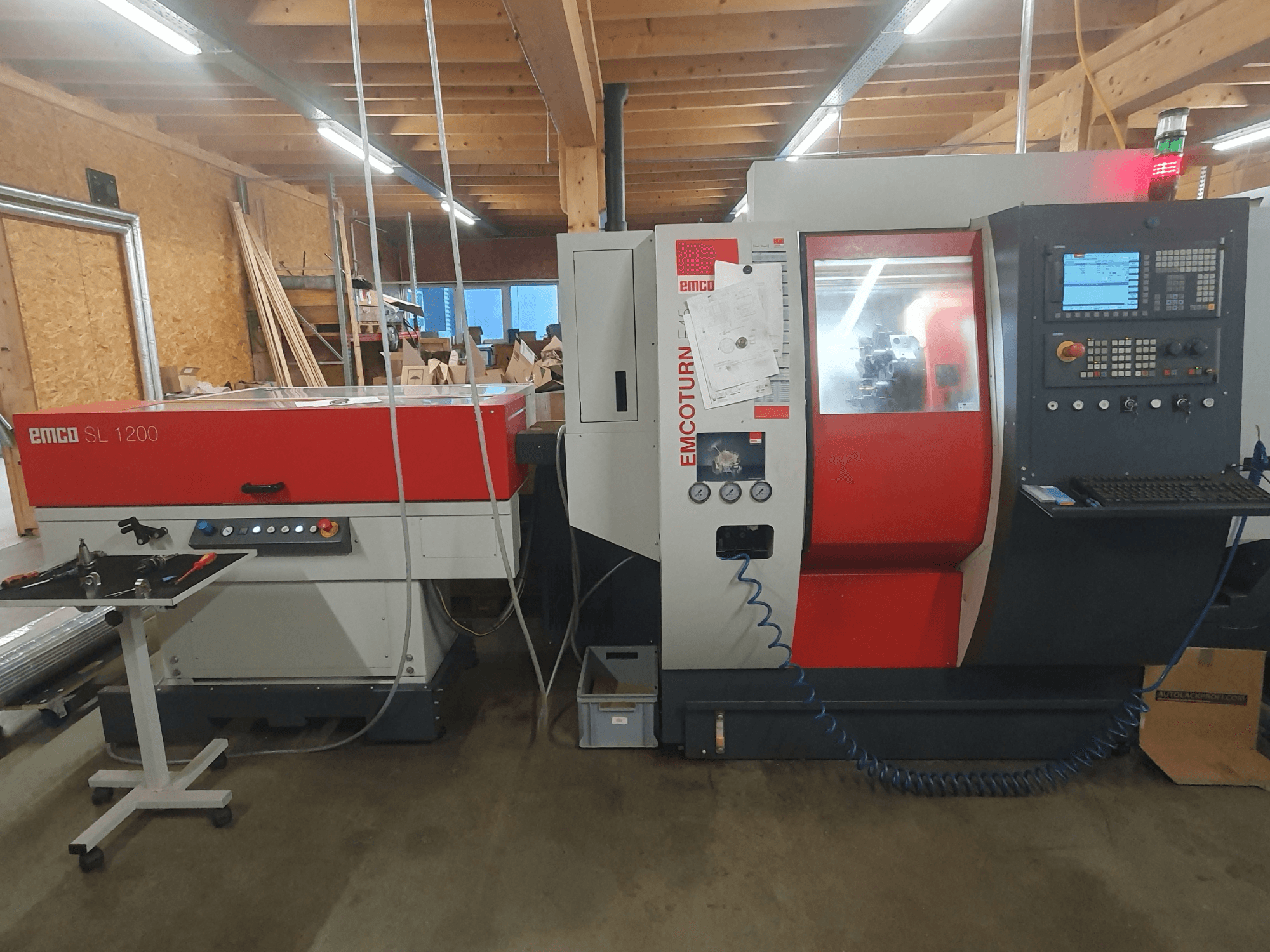 EMCO SL 1200 CNC-Drehmaschine und EMCOturn; Frontansicht mit Bedienelementen, Displays und Betriebsanzeigen in einer Werkstattumgebung.
