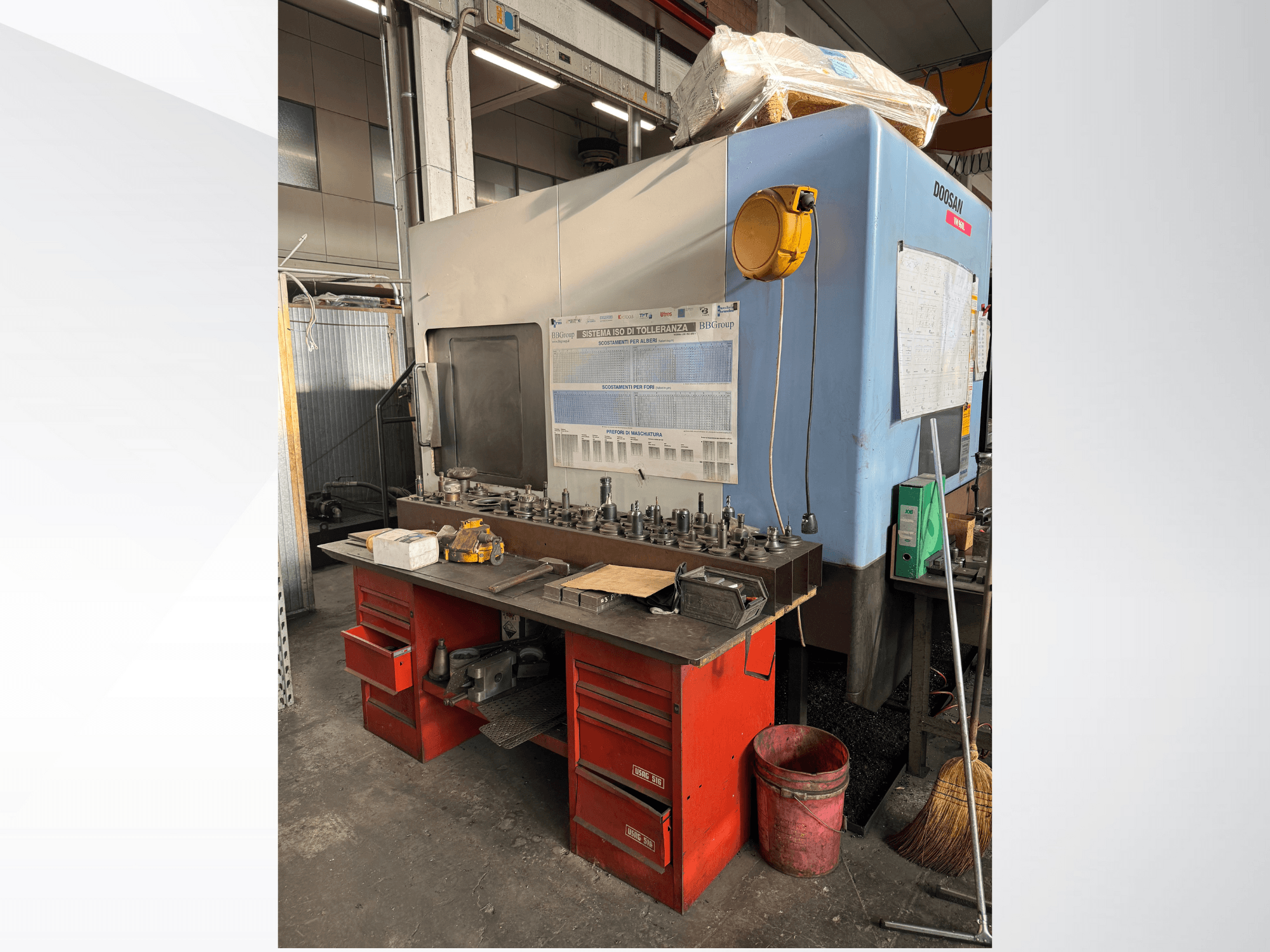 Doosan-Bearbeitungszentrum mit roter Werkbank und Stauraum für Werkzeuge und Ausrüstung, von vorne gesehen.