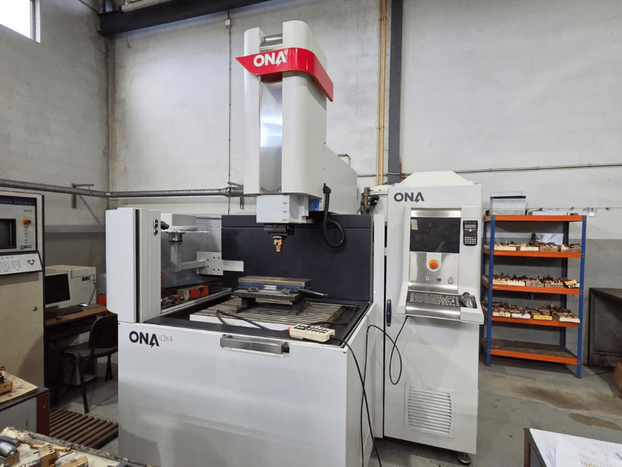 ONA QX4 Senkerodiermaschine in der Seitenansicht, mit Bedienfeld und Arbeitstisch, in einer Werkstatt.