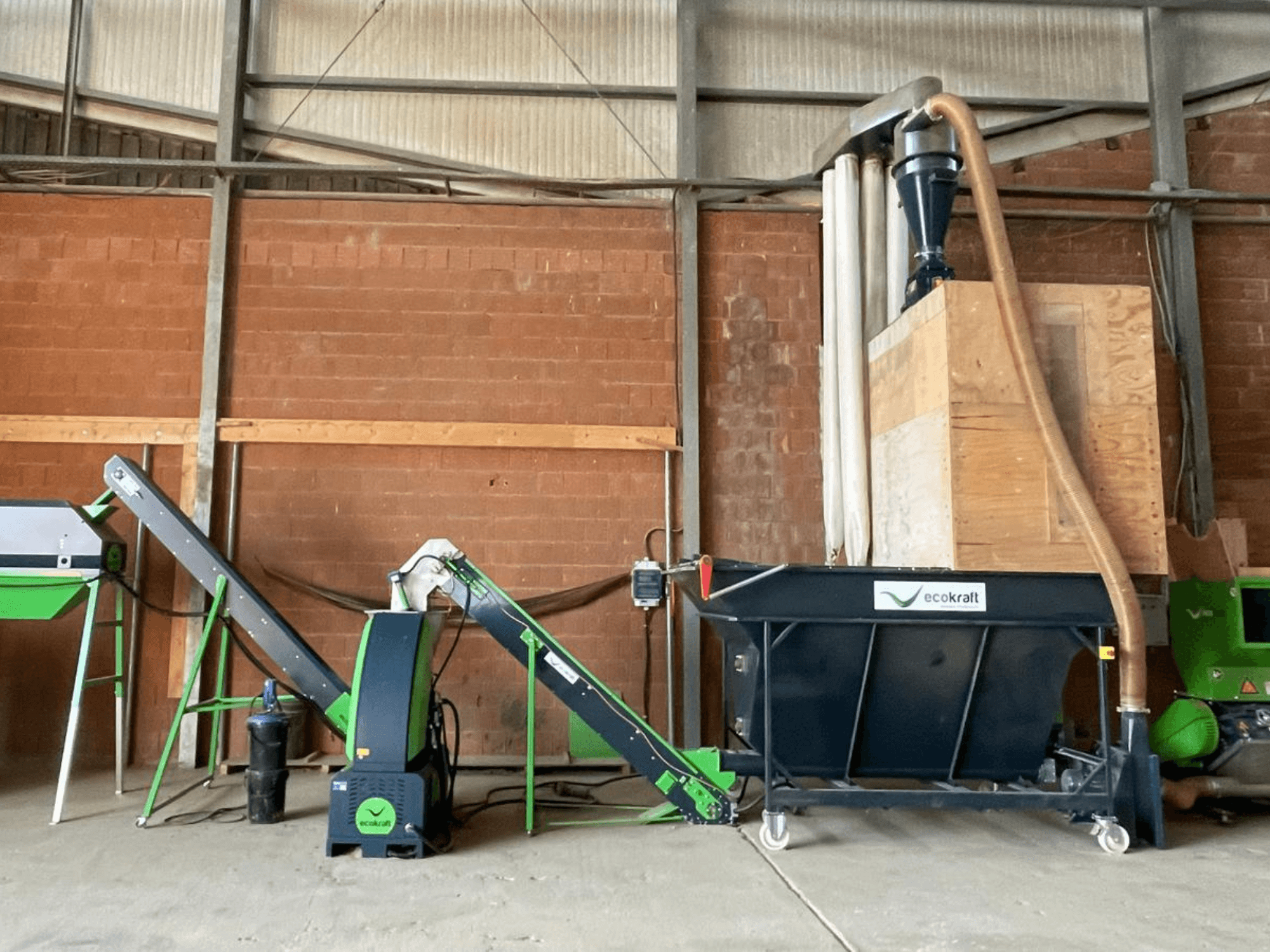 ECOKRAFT LP 22-Werkzeugmaschine in einer Lagerhalle, ausgestattet mit einem Förderband und einer Staubabsauganlage. Seitenansicht mit Hervorhebung der funktionalen Komponenten.