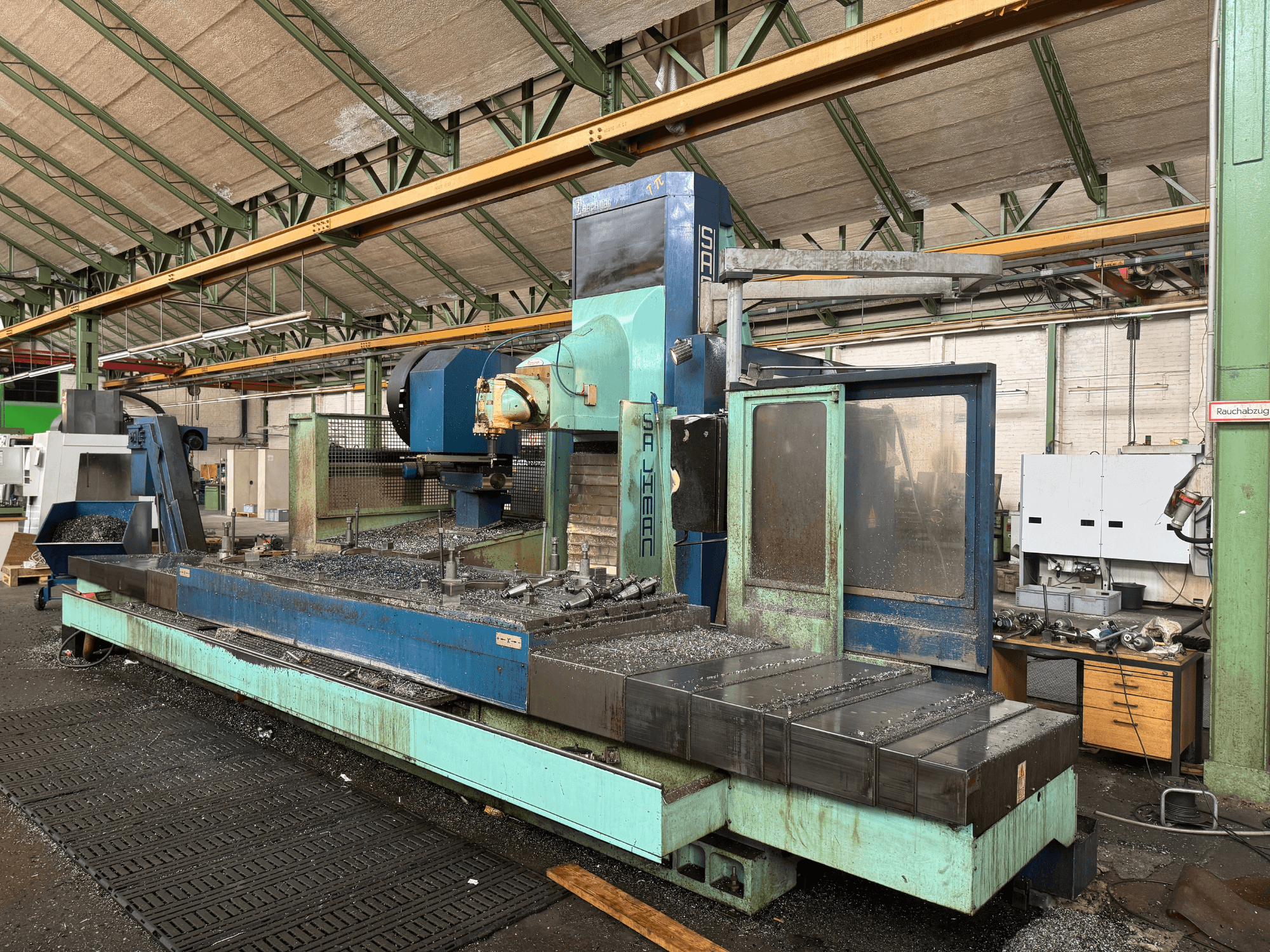 Salvador-Fräsmaschine in Werkseinstellung, Vorderansicht, mit blauem und grünem Farbschema, mit Metallspänen auf dem Bett.