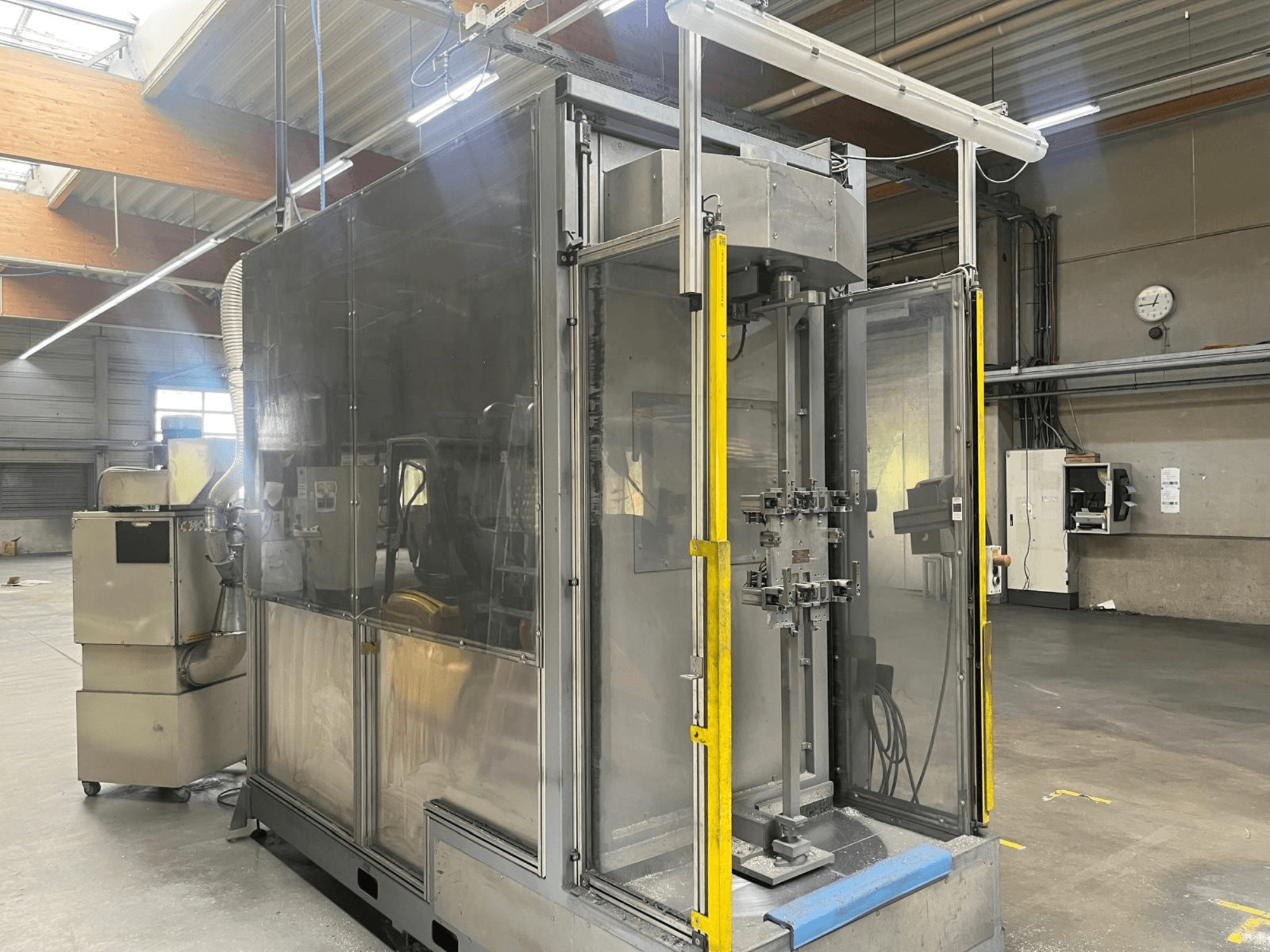 Eine Werkzeugmaschine vom Typ M.A.I. ASD 1 in Seitenansicht, mit transparenter Verkleidung und Bedienelementen an der Vorderseite, in einer Werkstatt.