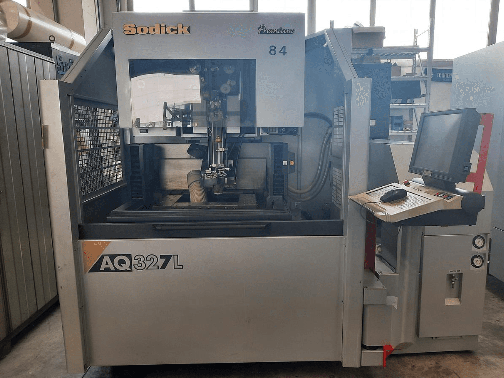 Sodick AQ327L Maschine in der Vorderansicht, mit Bedienfeld, Benutzeroberfläche und sichtbarem Schneidbereich im Inneren.