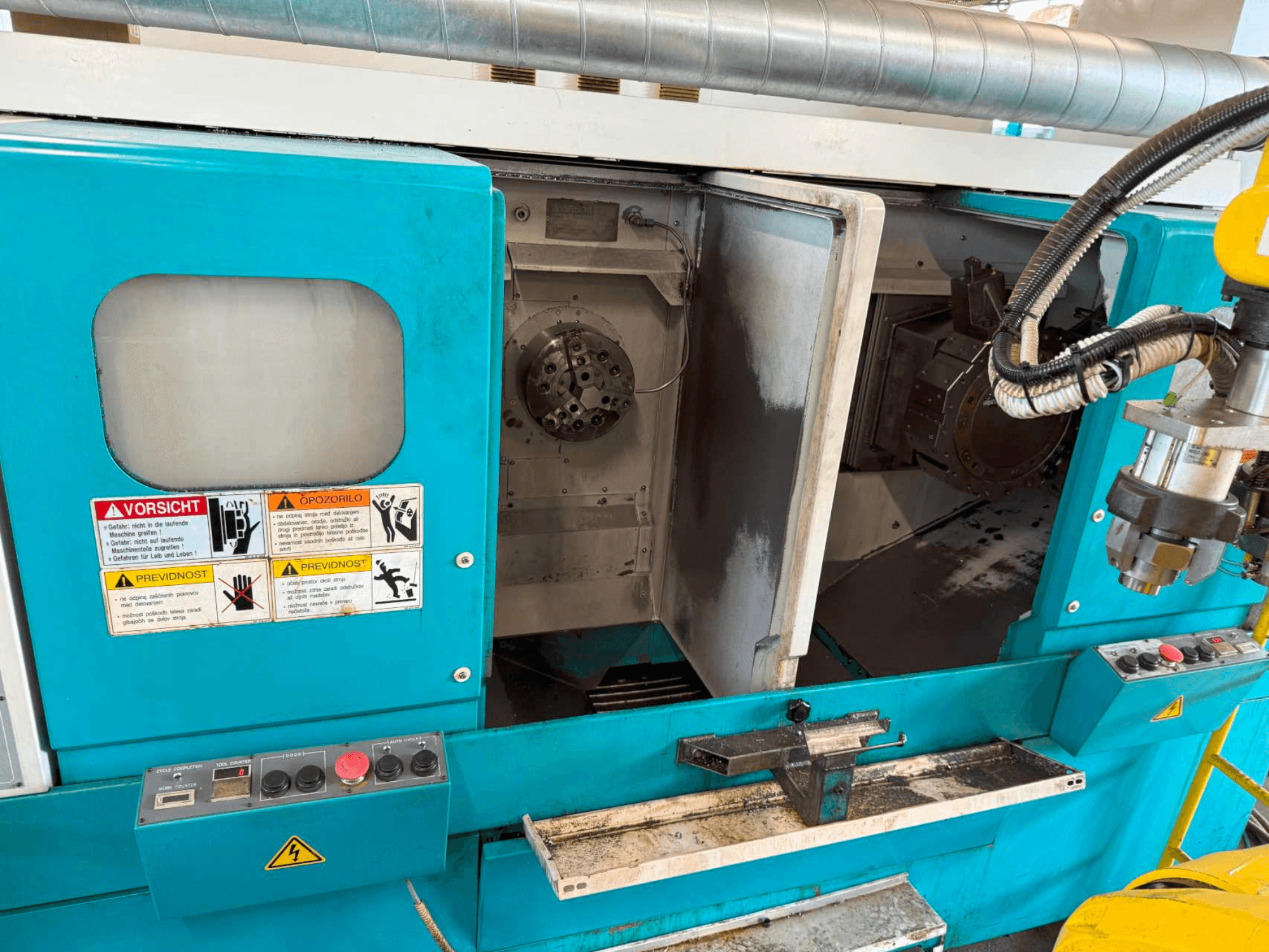 DOOSAN H310T Horizontaldrehmaschine, Vorderansicht mit Bedienfeld und Spindelbereich mit Sicherheitshinweisen.