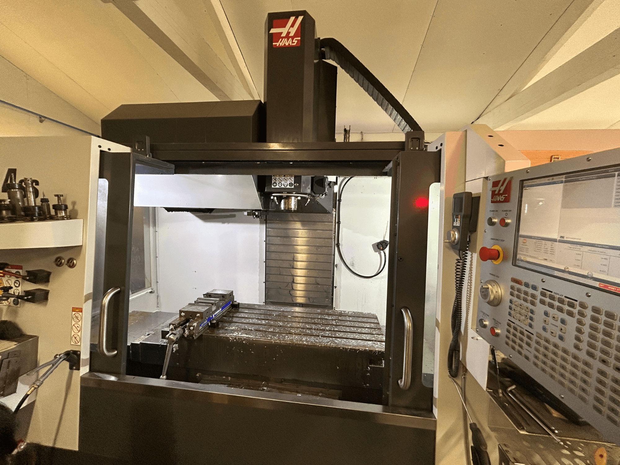 HAAS VF-4SS Vertikal-Bearbeitungszentrum, Vorderansicht, mit Bedienfeld, Werkzeughalter und Arbeitsbereich mit Metallspänen.