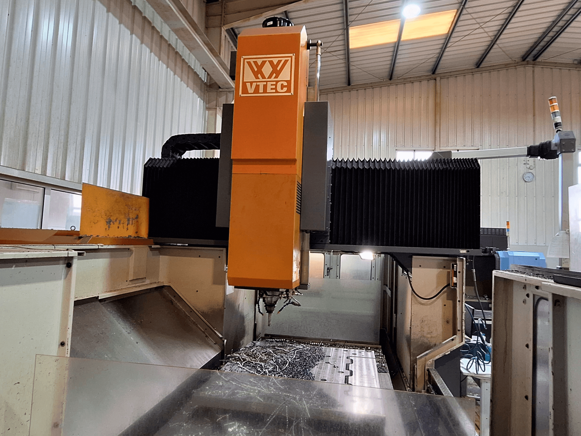 Portalfräsmaschine von PORTIC, Modell VTEC, in der Vorderansicht mit sichtbarem Schneidwerkzeug und Metallspänen.