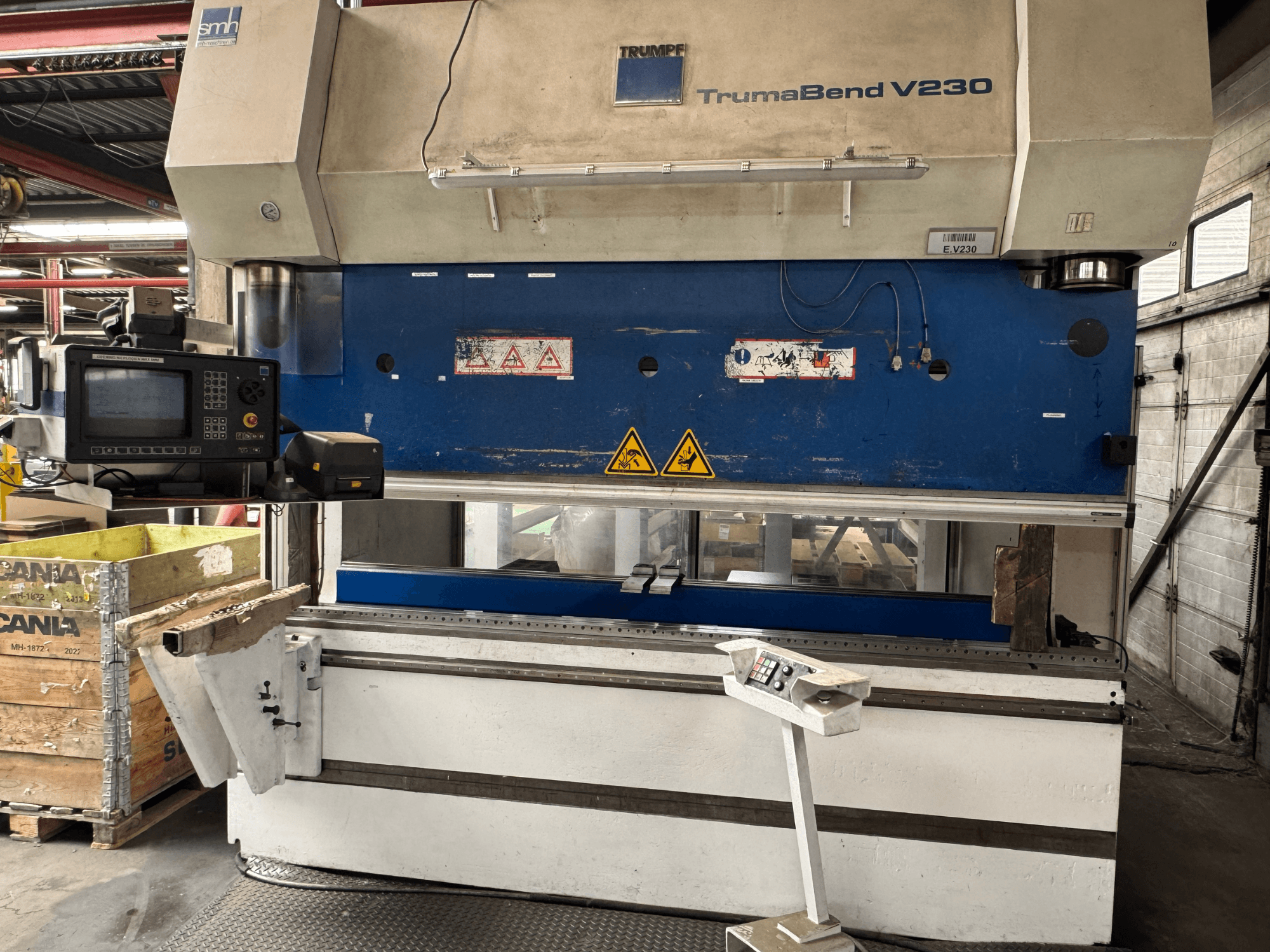 TRUMPF Abkantpresse TrumaBend V230, Vorderansicht mit Bedienfeld, Warnschildern und einem Werkstückträgerarm sichtbar.