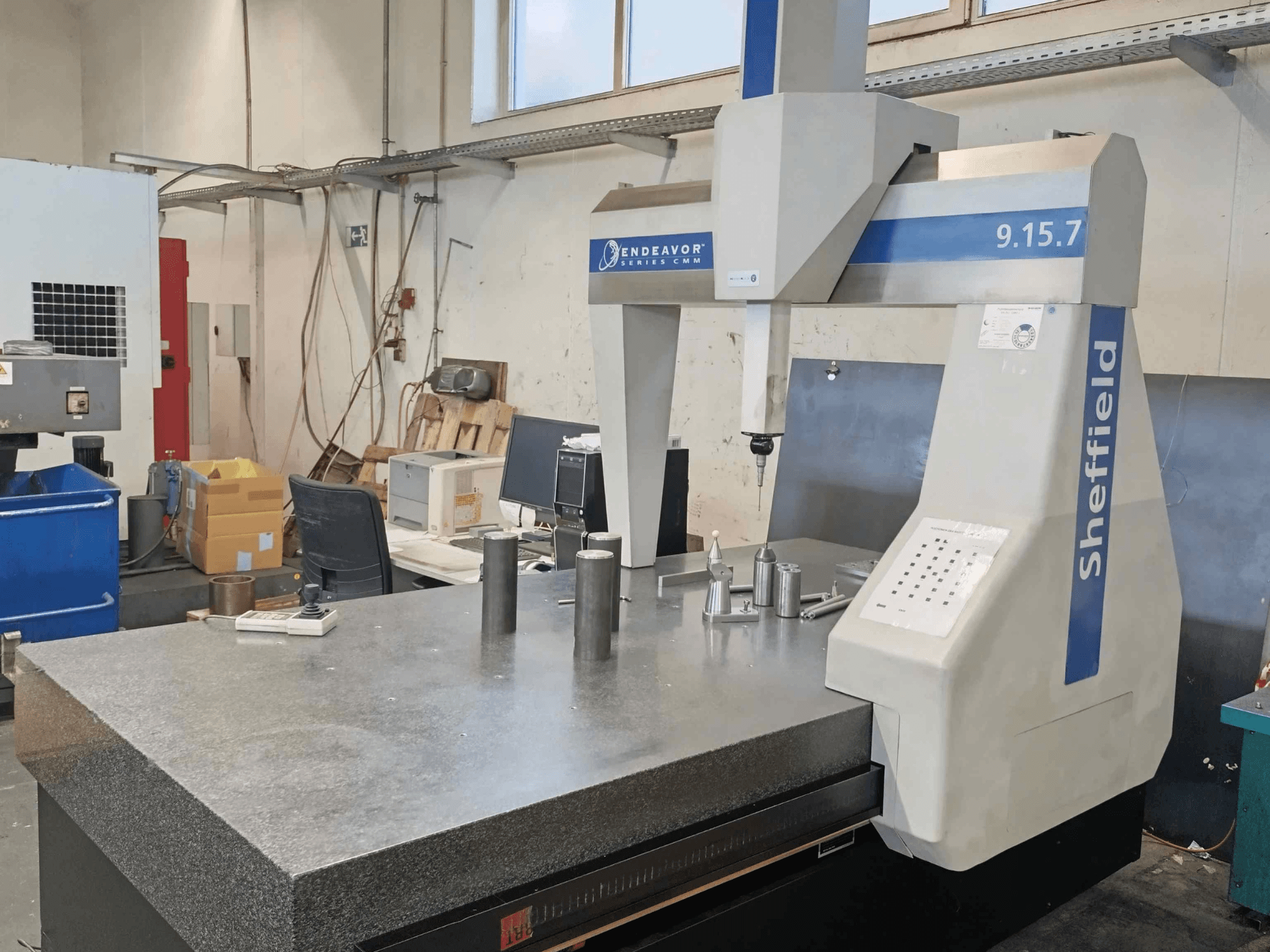 Koordinatenmessgerät Sheffield Endeavor 9.15.7 in einer Werkstatt mit einem Granittisch und metallischen Werkstücken.