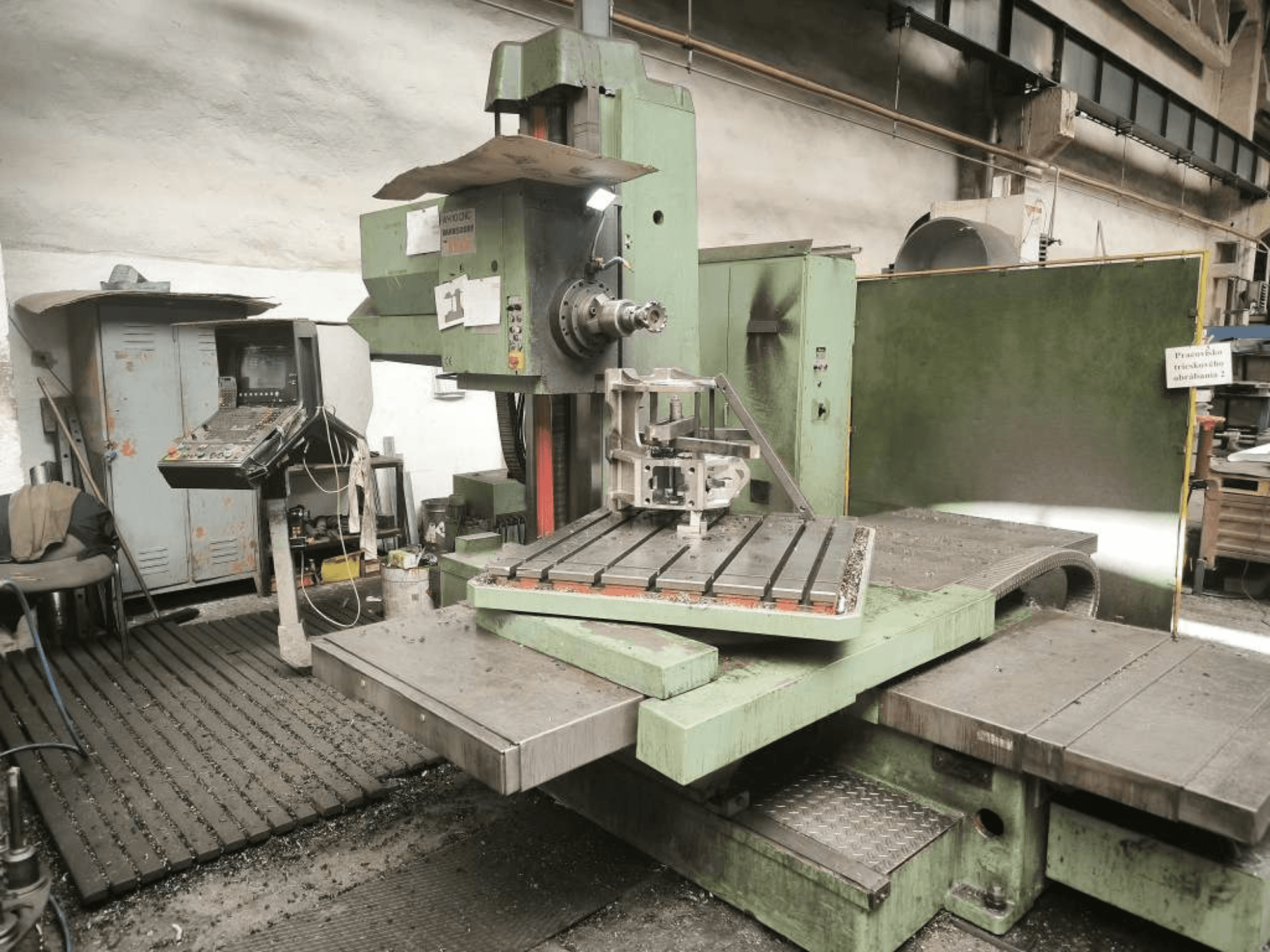 Die CNC-Bohrmaschine TOS WH 10 von vorne gesehen, mit einem bearbeiteten Werkstück auf dem Tisch und dem Bedienfeld.
