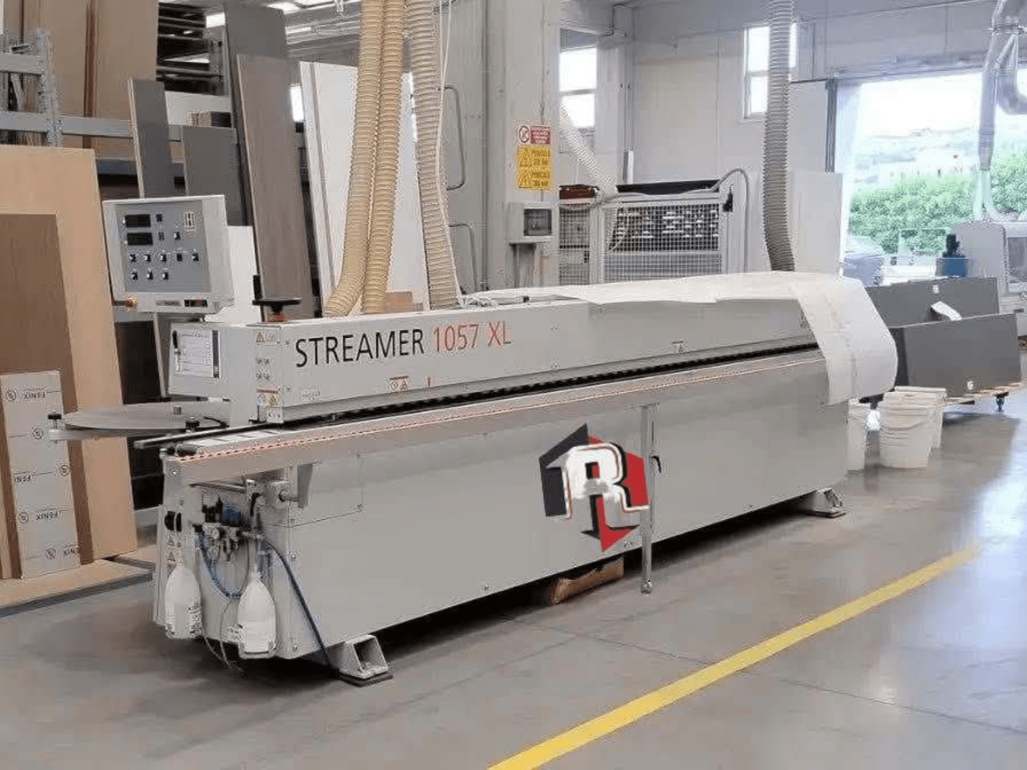 HOLZHER STREAMER 1057 XL Kantenanleimmaschine in einer Werkstatt, Seitenansicht mit sichtbarem Bedienfeld und Luftschläuchen.