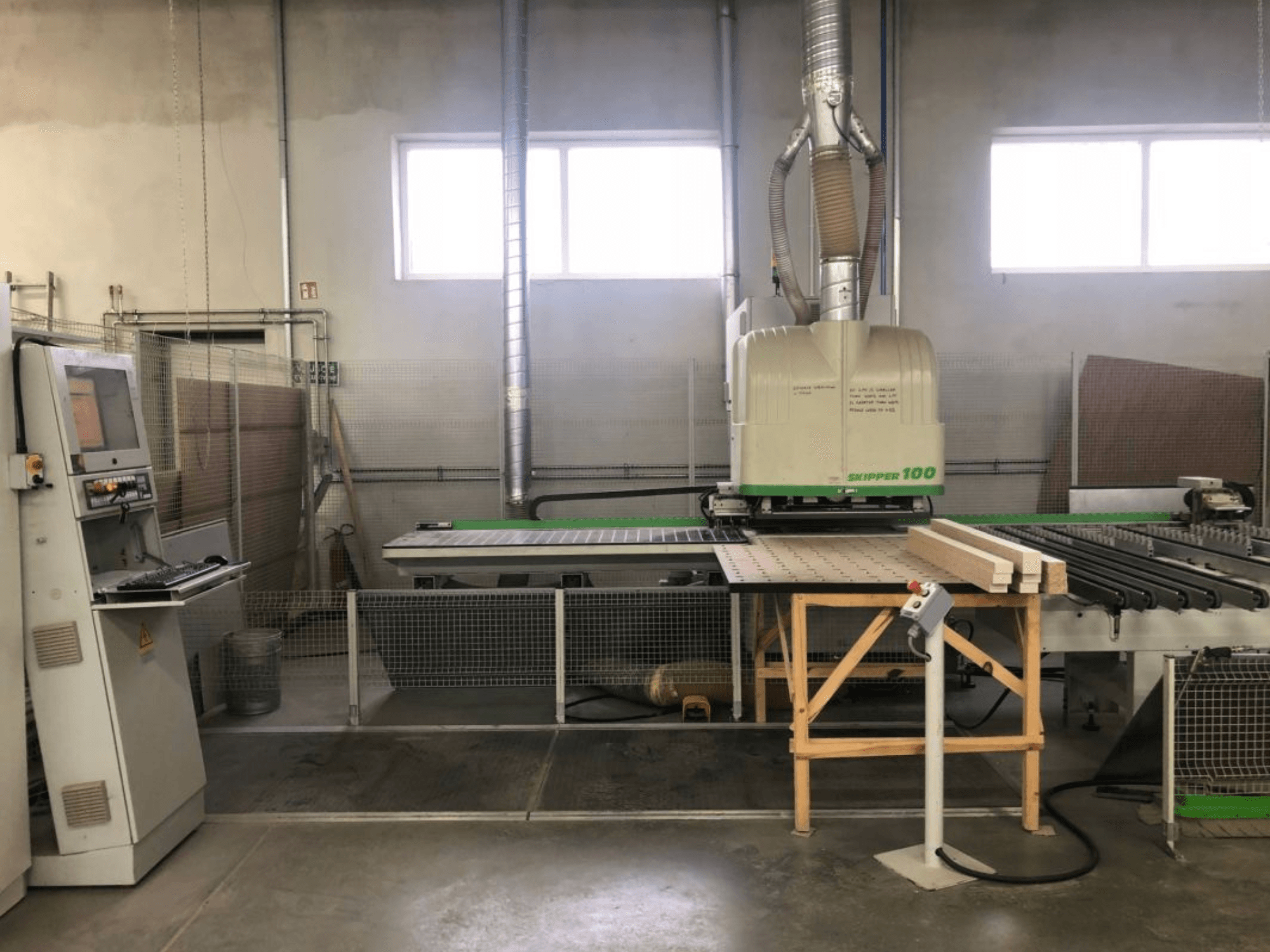 BIESSE SKIPPER 100 CNC-Bearbeitungszentrum in einer Werkstatt; die Vorderansicht zeigt die Maschine mit Bedienfeld und Holz auf dem Arbeitstisch.