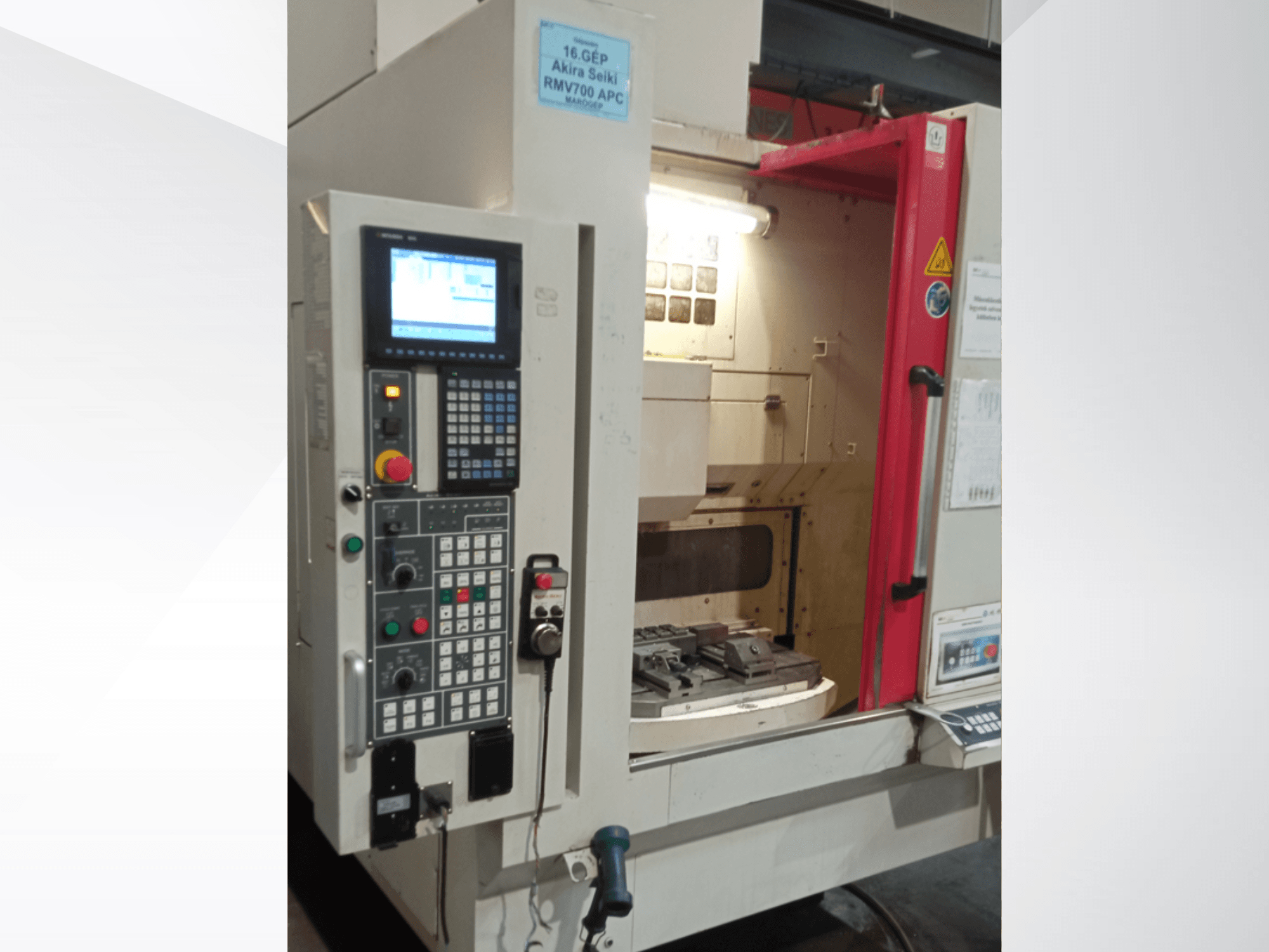 Akira Seiki RMV 700 APC Vertikal-Bearbeitungszentrum in der Vorderansicht, mit digitalem Bedienfeld und Arbeitsbereich mit Werkzeugen.