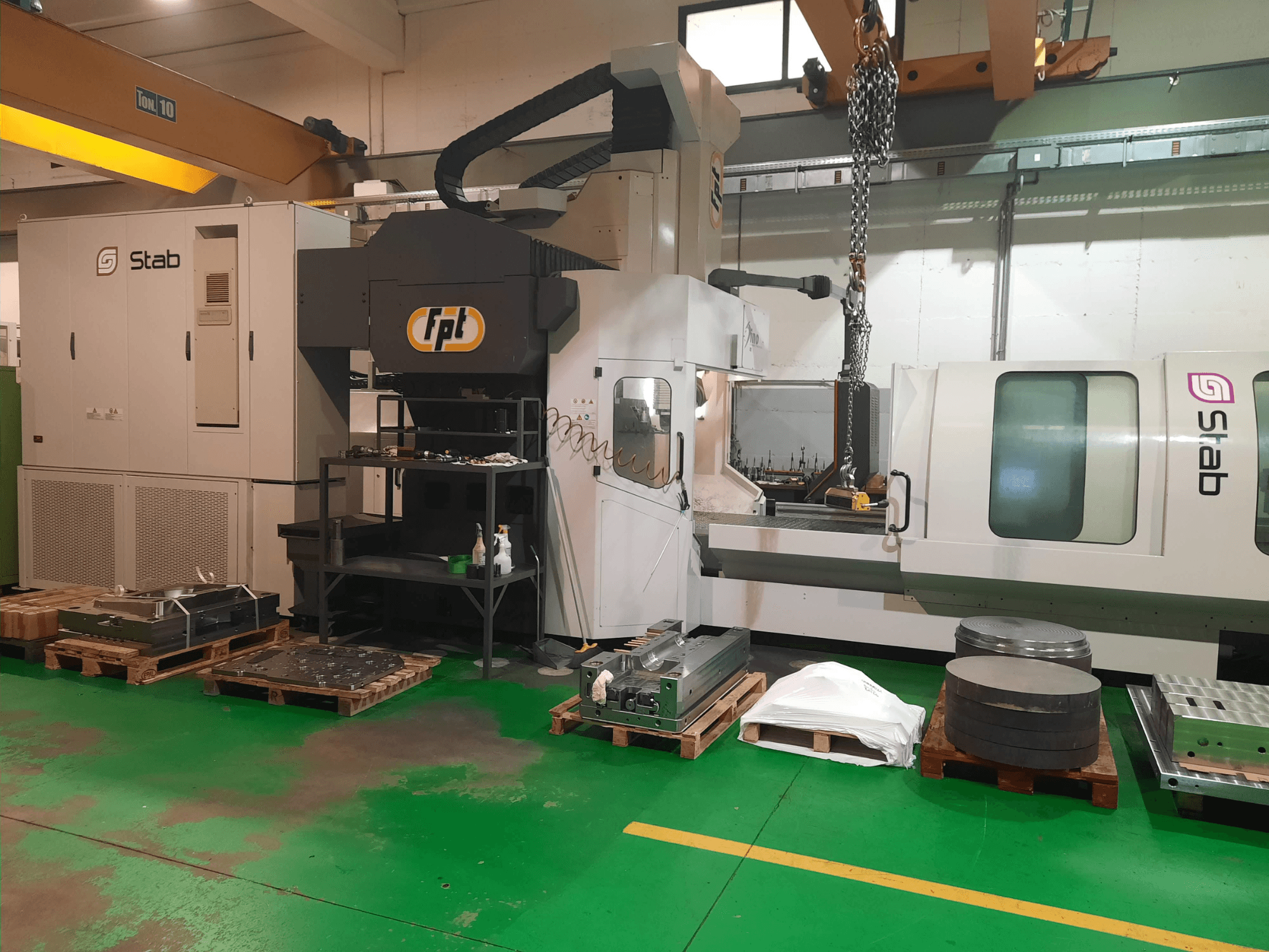 FPT DINO Bettfräsmaschine in einer Werkstatt, von vorne gesehen, mit nahegelegenen Werkzeugen und Materialien auf Paletten.
