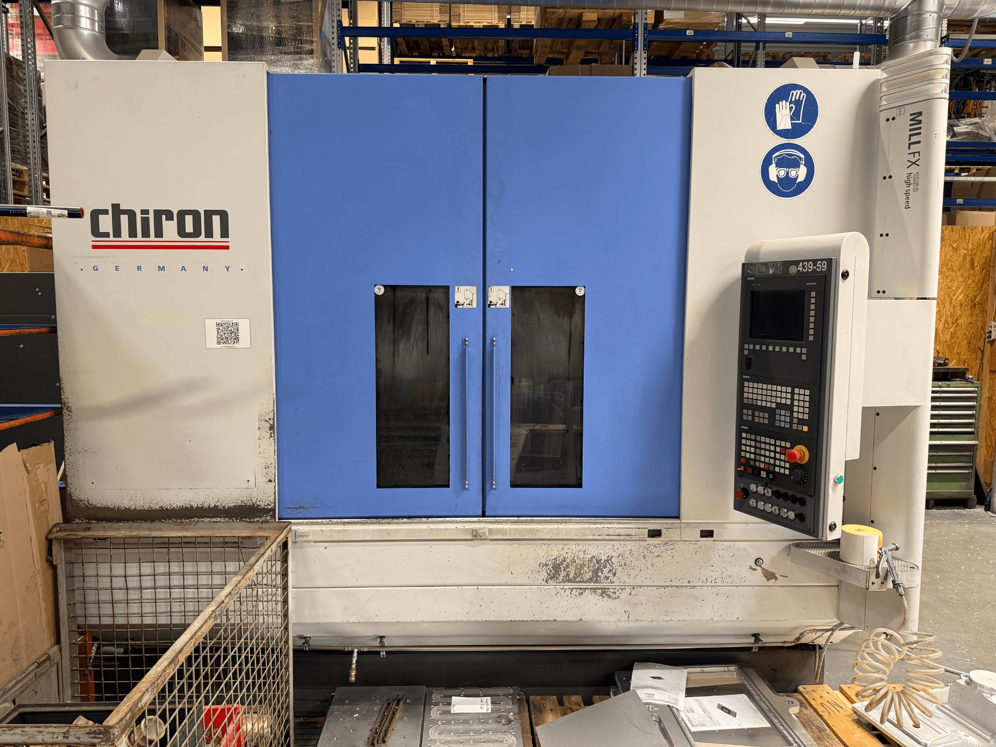 Vertikales Bearbeitungszentrum CHIRON MILL FX 1250, Vorderansicht, mit Bedienfeld und Sicherheitssymbolen, bereit für Präzisionsarbeiten.