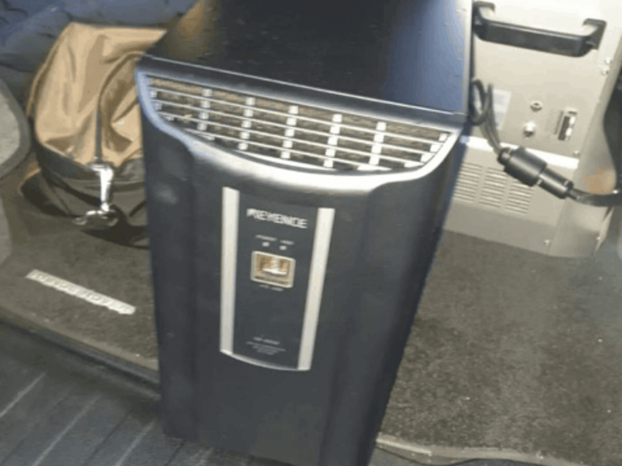 KEYENCE IM-8030-Automatisierungssystem in einer Frontansicht mit Bedienfeld und Lüftungsöffnungen vor dem Hintergrund des Fahrzeuginnenraums.