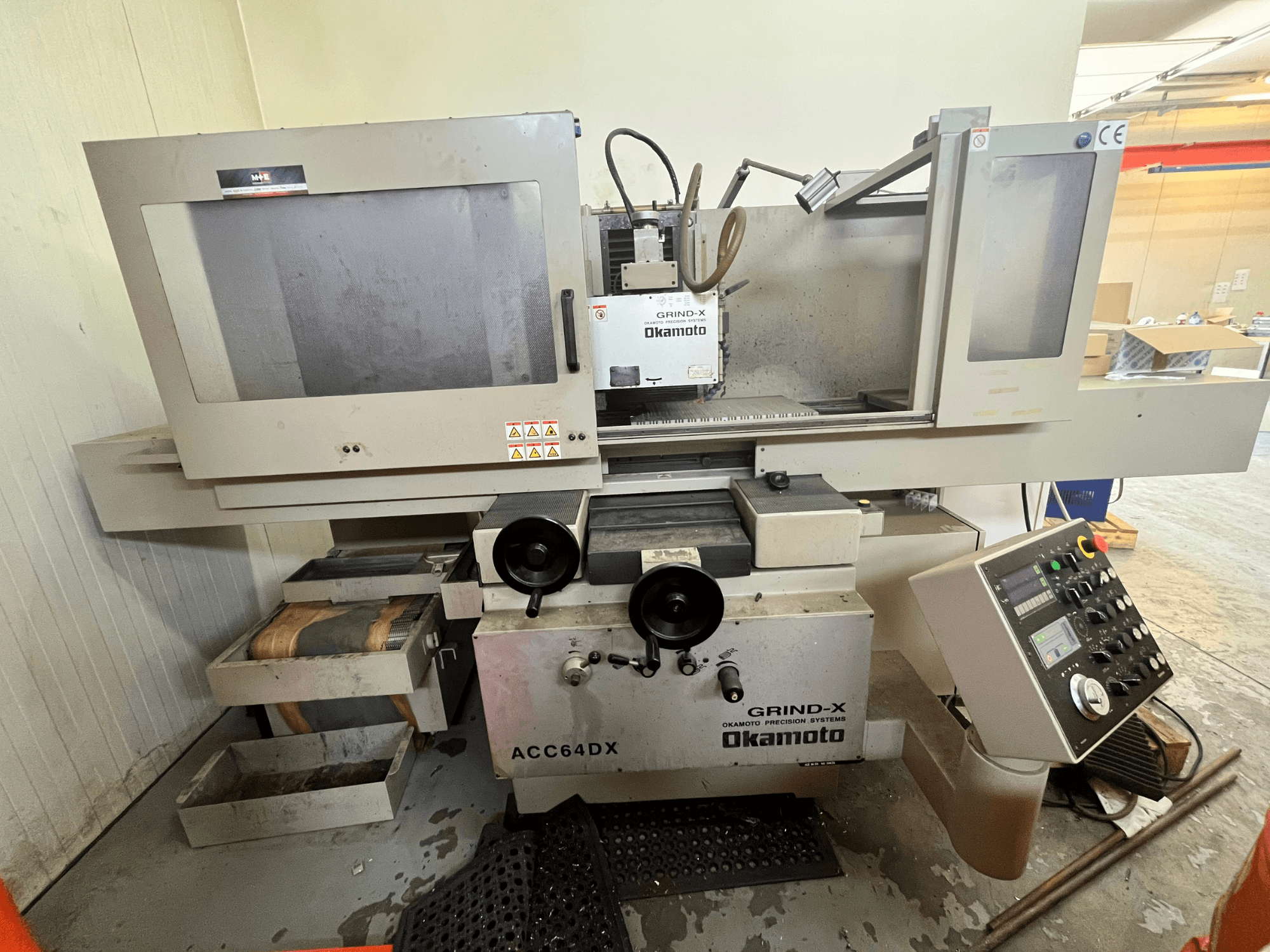 Okamoto ACC64 DX-Flachschleifmaschine in der Vorderansicht, mit Schleifscheibe, Bedienfeld und Schubladen.