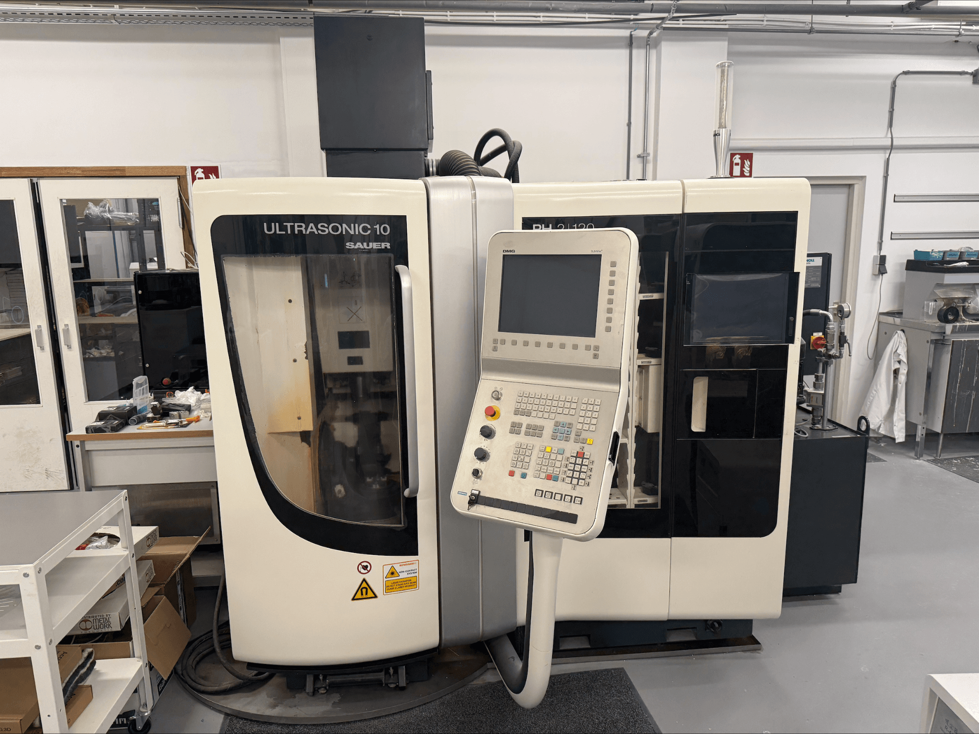 DMG Sauer Ultrasonic 10 + PH 2 | 120 vertikales Bearbeitungszentrum, Vorderansicht, mit Bedienpult und großem Sichtfenster.