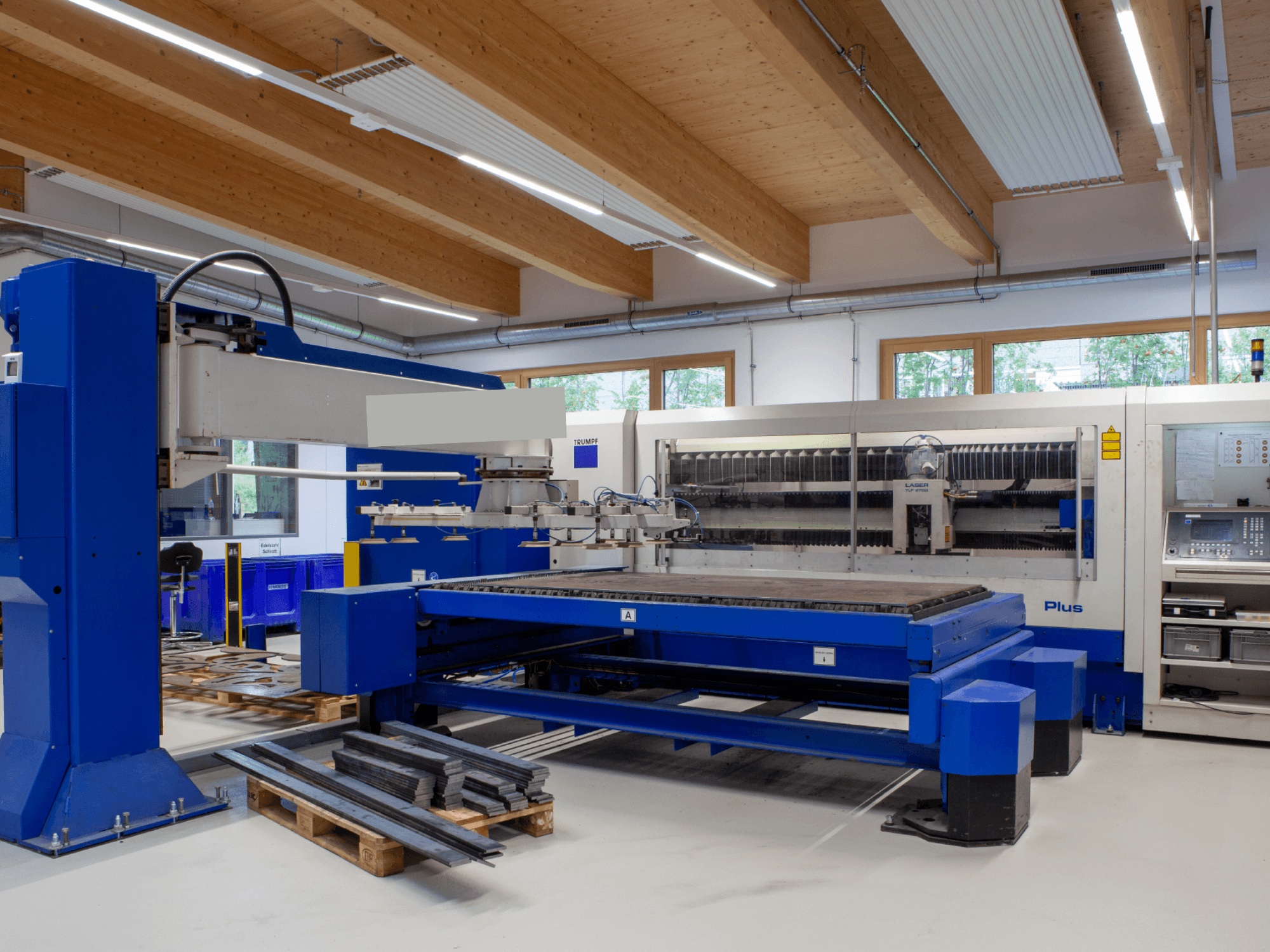 TRUMPF TRUMATIC L 2530 Plus CO₂-Laserschneidmaschine in einer Werkstatt, die sich durch ein großes Schneidbett und ein industrielles Design auszeichnet.
