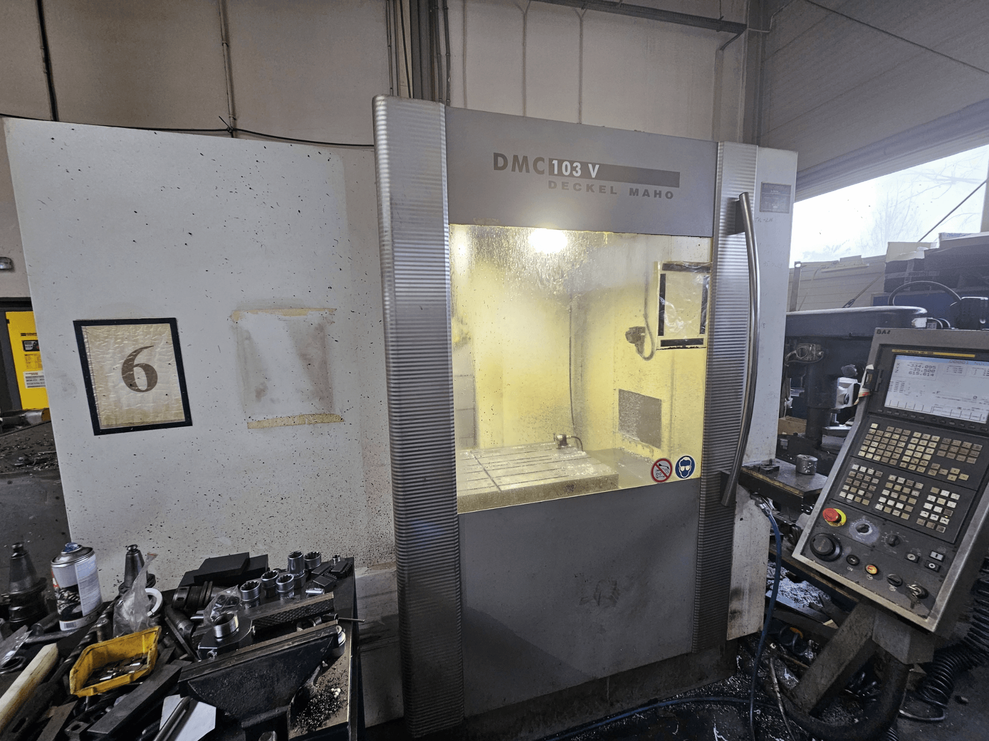 Deckel Maho DMC 103 V CNC-Maschine, Vorderansicht, mit Bedienpult und Arbeitsraum, mit der Nummer "6" an der Wand.