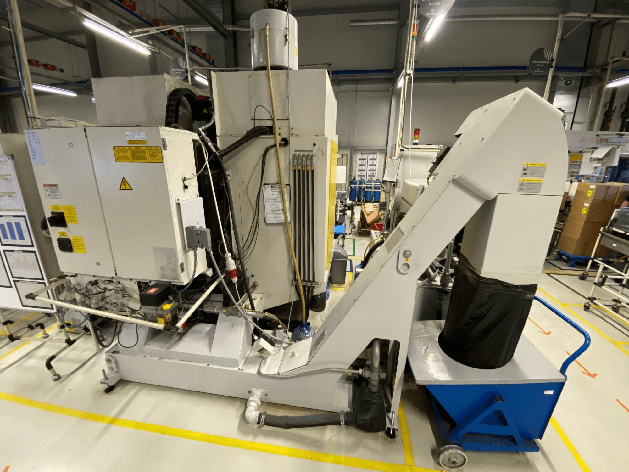 FANUC ROBODRILL α-D21LiB vertikales Bearbeitungszentrum in der Vorderansicht, mit den elektrischen Komponenten und dem Auswurfschacht.