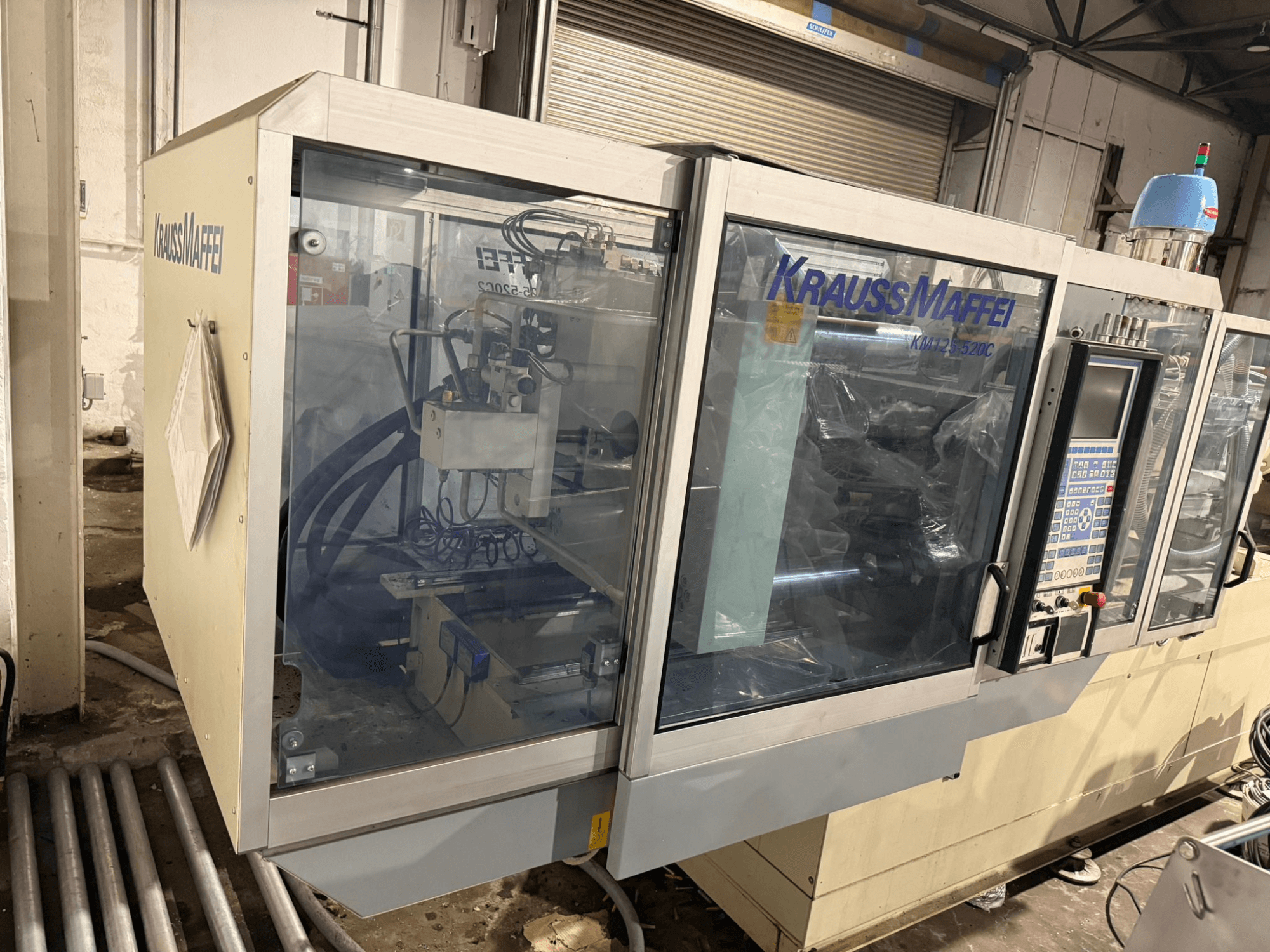 Krauss Maffei KM125-520C2 hydraulische Spritzgießmaschine, Frontansicht mit Bedienfeld und transparentem Gehäuse.