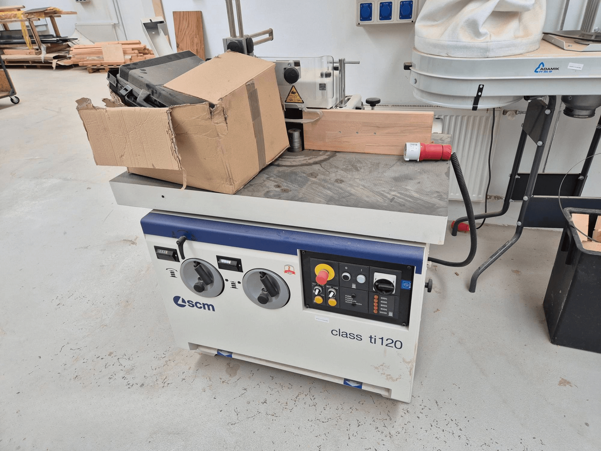 SCM-Klasse ti120 Holzbearbeitungsmaschine, Vorderansicht, mit einem Bedienfeld mit Knöpfen und Tasten sowie einem angebrachten Karton.