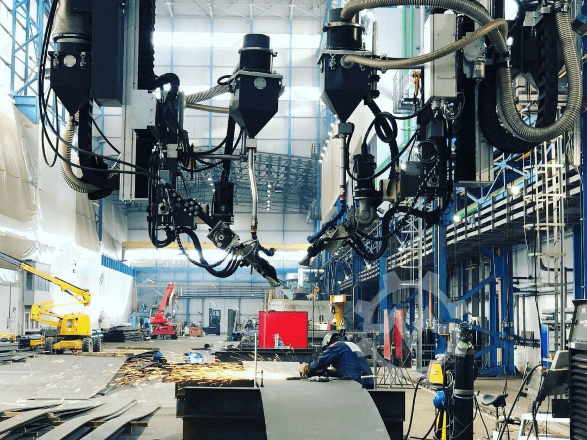 Roboter-Schneidemaschine in einer industriellen Umgebung, mit Funkenflug, von der Seite gesehen; mit mehreren Anbaugeräten und Schläuchen.