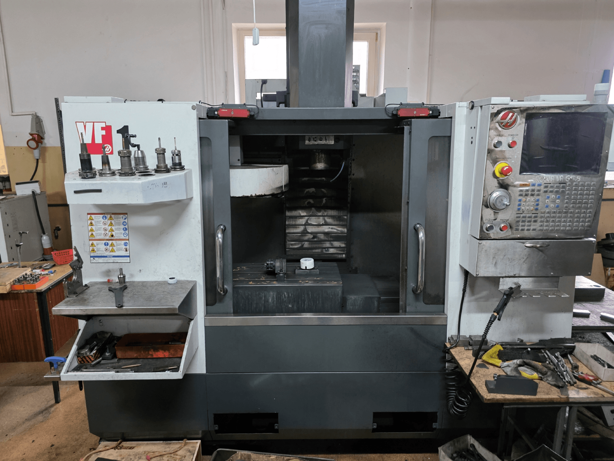 CNC-Fräsmaschine der Serie VF von Haas, Vorderansicht; mit mehreren Werkzeughaltern, Bedienfeld und sichtbarem Arbeitsbereich.