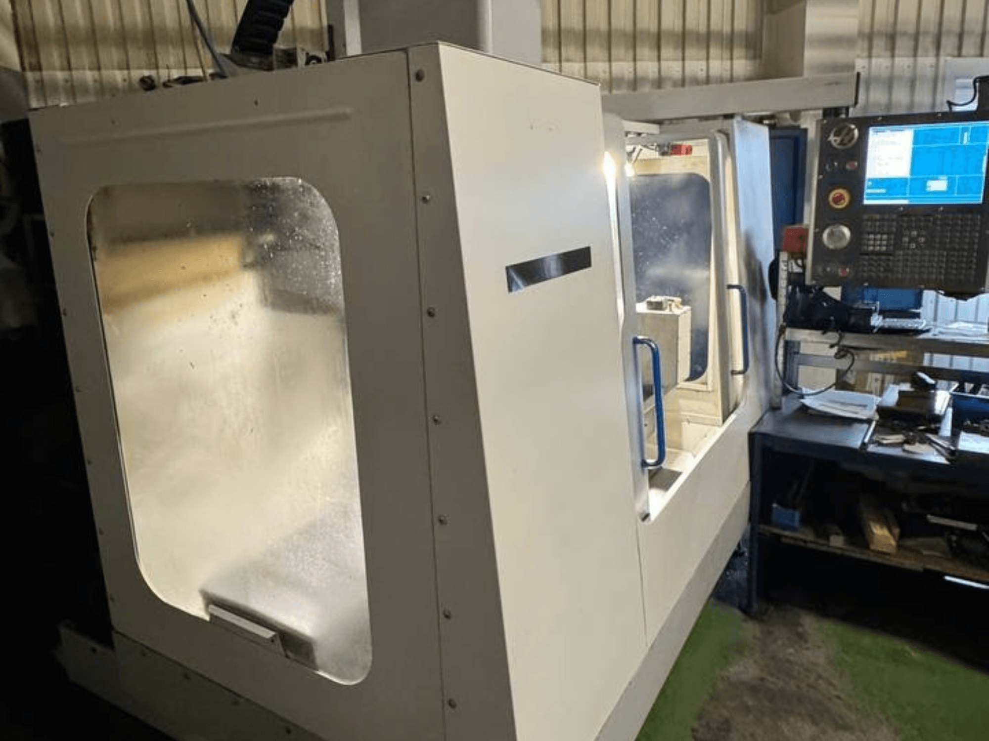 HAAS VCE 750 Vertikal-Bearbeitungszentrum in der Seitenansicht, mit Bedienpult und durchsichtiger Sicherheitsabdeckung.