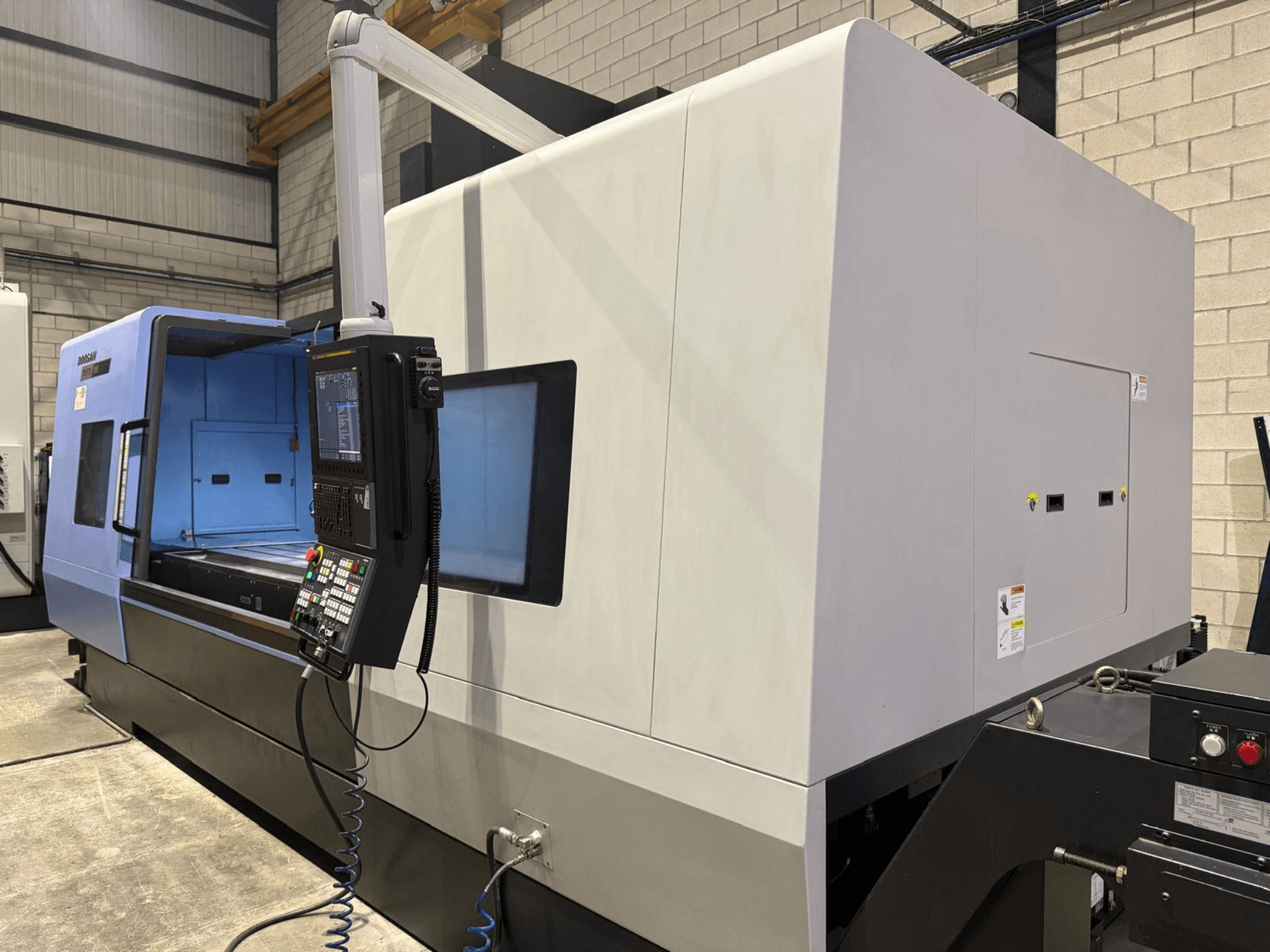 Industrielle CNC-Drehmaschine, blau-graues Äußeres, Vorderansicht; verfügt über ein Bedienfeld mit Tasten und Display für präzise Arbeitsvorgänge.