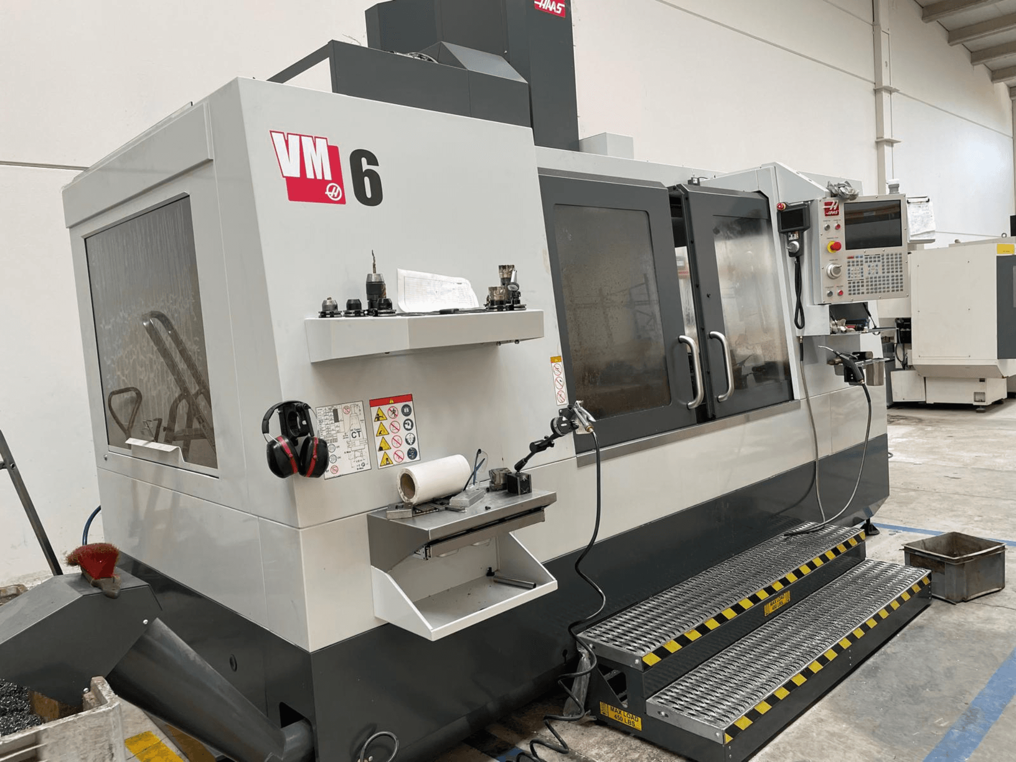 Haas VM-6 Vertikal-Bearbeitungszentrum, Vorderansicht mit Bedienfeld, Werkzeughaltern und Sicherheitsfunktionen.