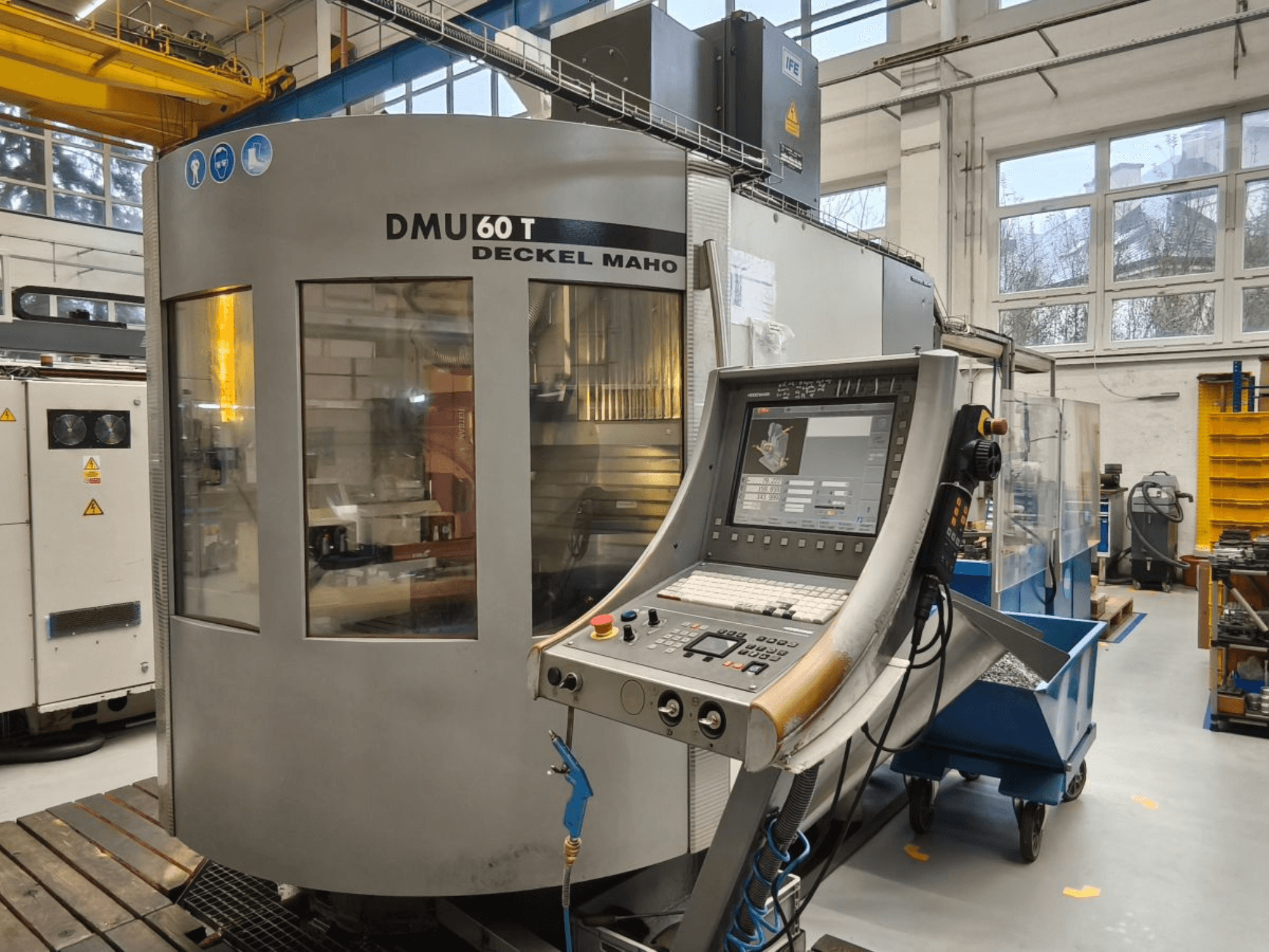 Vertikale Ansicht eines DECKEL MAHO DMU 60T Bearbeitungszentrums mit Bedienpult, das Präzisionswerkzeuge in einer Werkstatt zeigt.