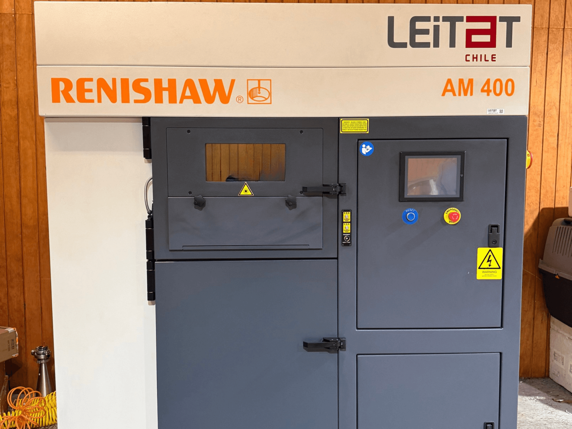 Vorderansicht des RENISHAW AM400 3D-Metalldruckers mit Bedienfeld, Warnhinweisen und Wartungszugang.