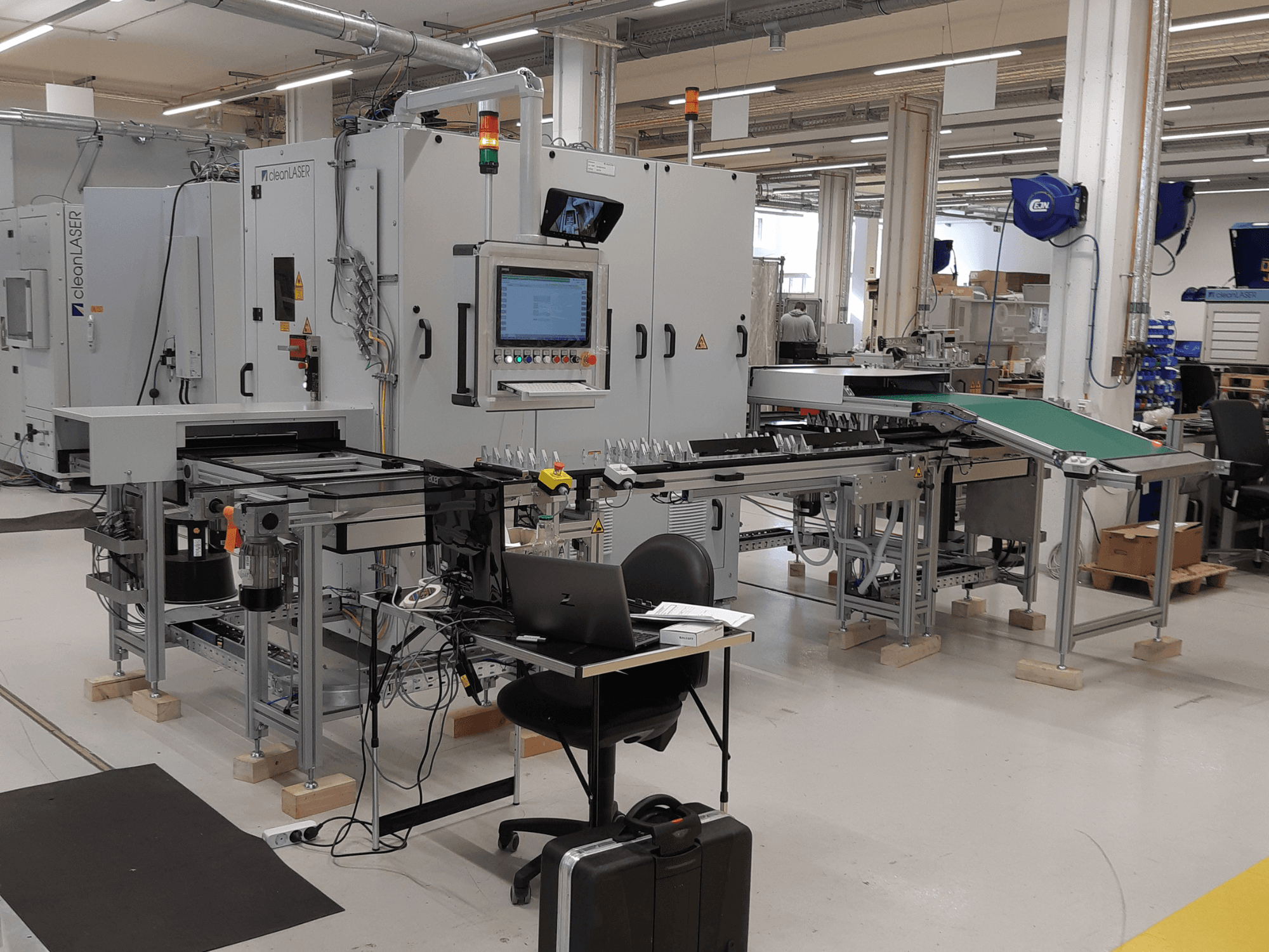 CLEAN LASER clean CELL 3220 CL600 Werkzeugmaschine, Vorderansicht, mit Bedienfeld, Förderband und Arbeitsbereich, aufgenommen in einer Werkstattumgebung.