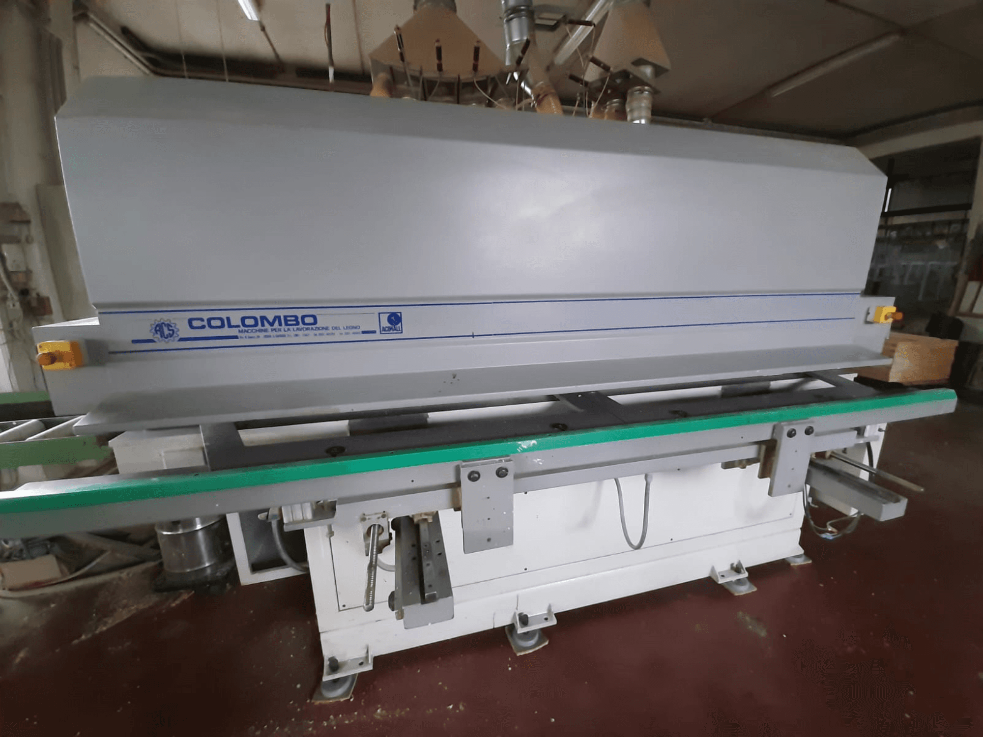 Colombo-Holzbearbeitungsmaschine, Vorderansicht, mit einem langen grünen Tisch, Bedientasten und einem grauen Gehäuse mit blauen Akzenten.