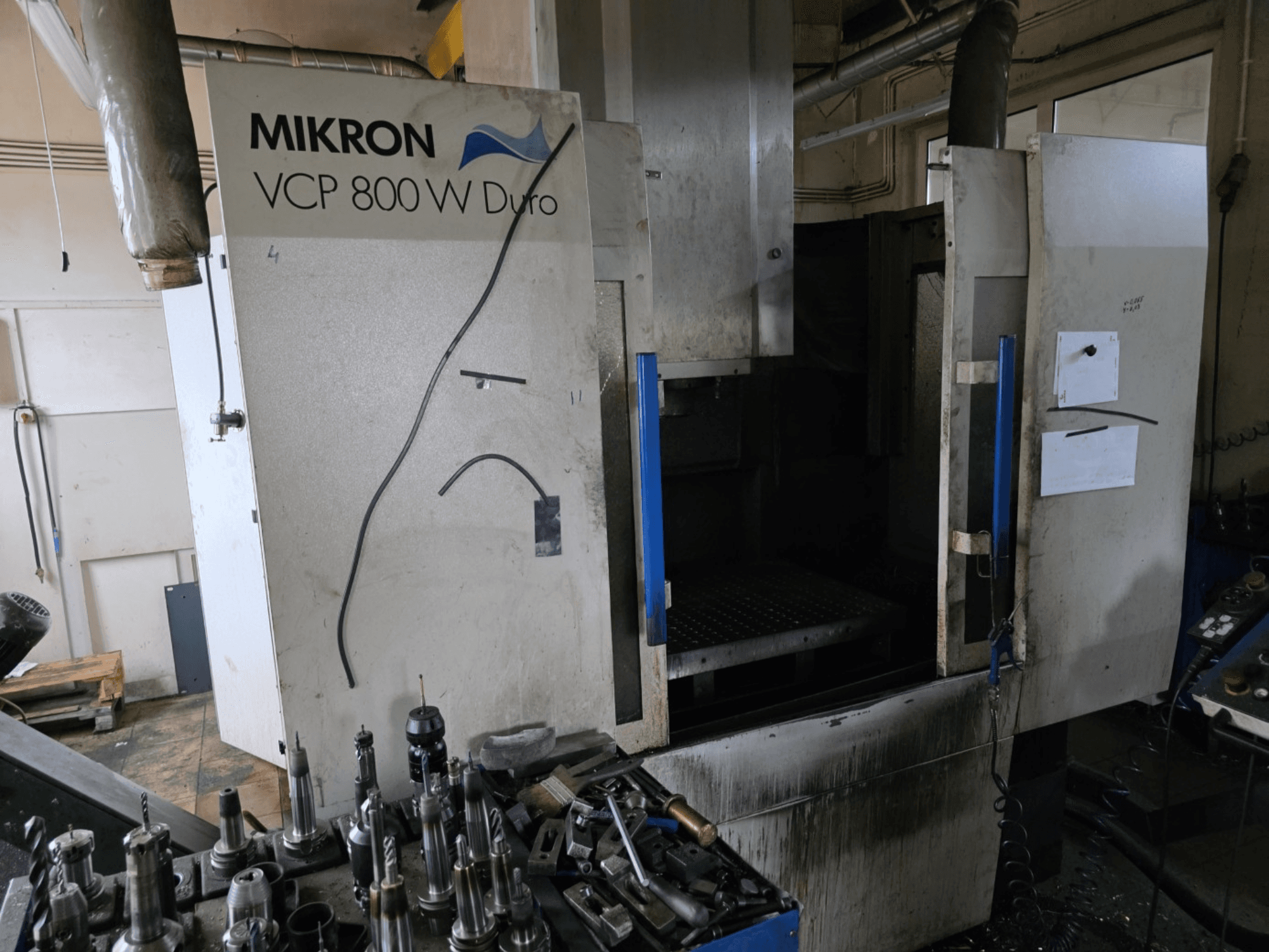 Mikron VCP 800 W Duro Fräsmaschine in der Seitenansicht, mit Werkzeugen und Bedienelementen im Vordergrund.