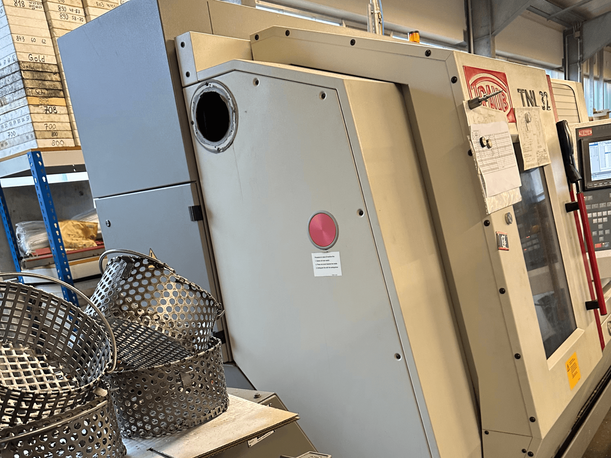 TRAUB TNL 32 P Drehmaschine nach Schweizer Art in Seitenansicht, im Vordergrund sind Werkstückkörbe zu sehen.