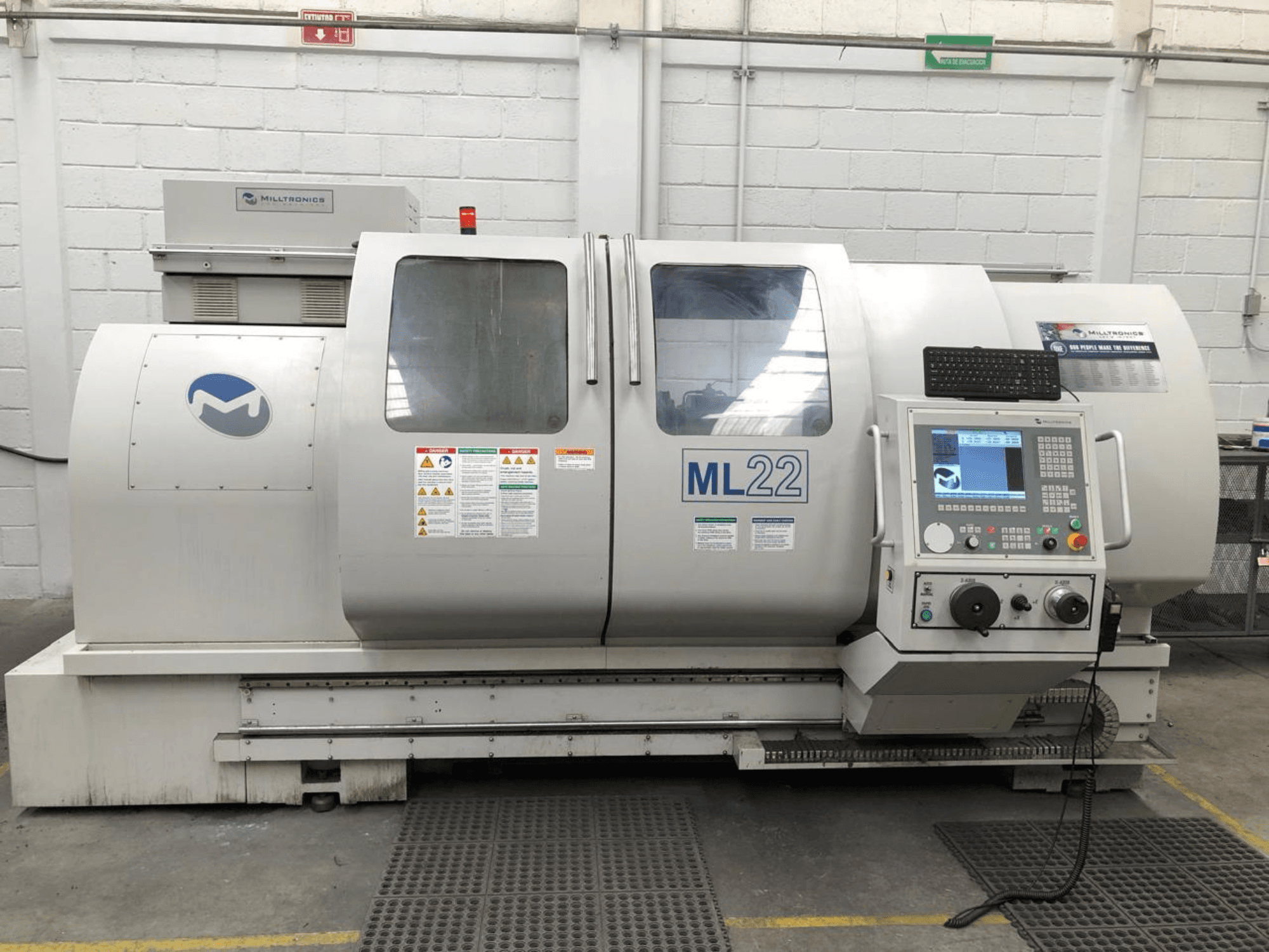 Vertikal-Bearbeitungszentrum MILLTRONICS RH 20, Frontansicht mit Bedienfeld, Markenlogo und Sicherheitsschildern an der Maschine.