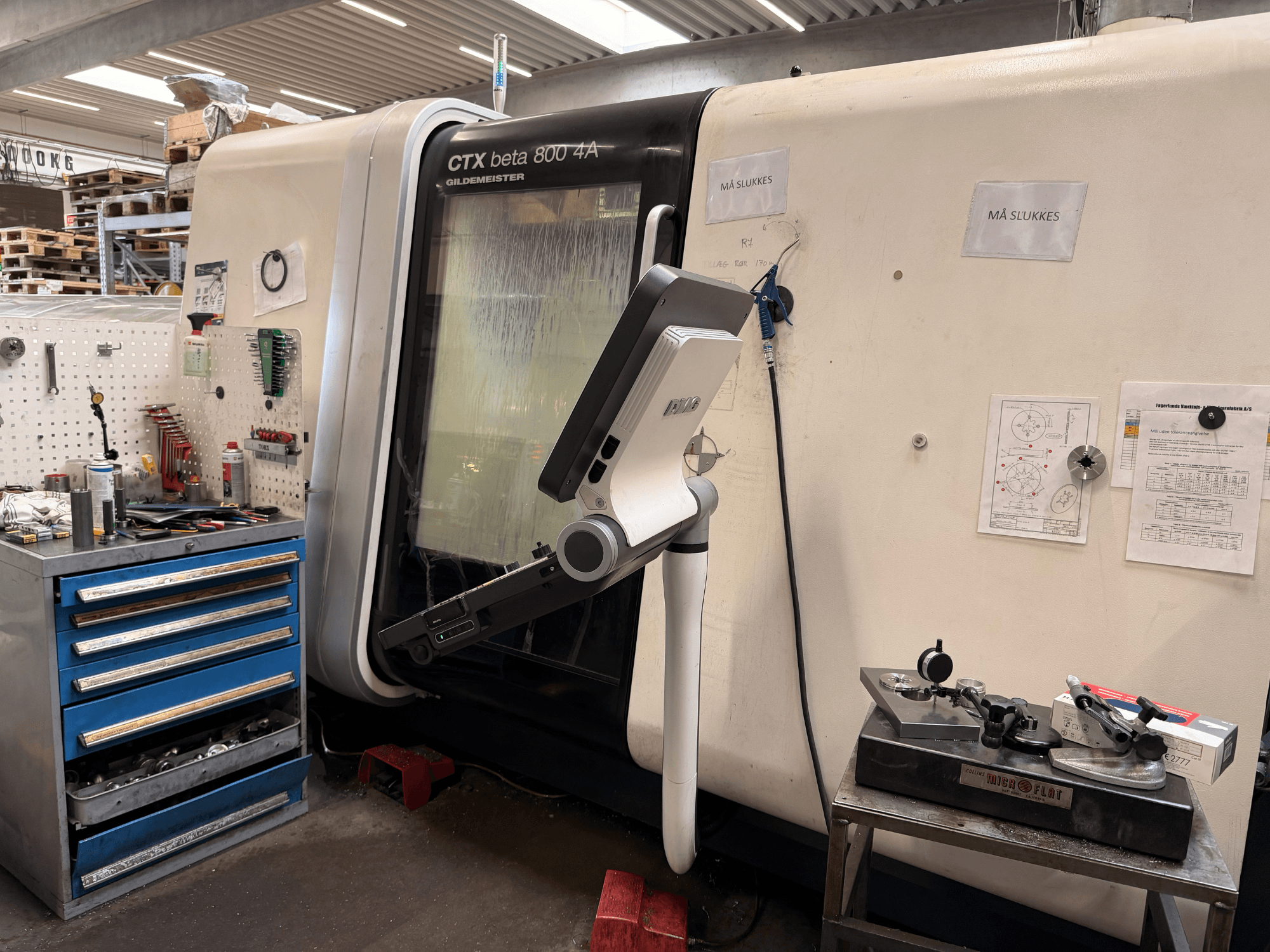 DMG MORI CTX Beta 800 4a Vertikaldrehmaschine in einer Werkstatt, mit einem Steuerarm und technischen Unterlagen in der Nähe.