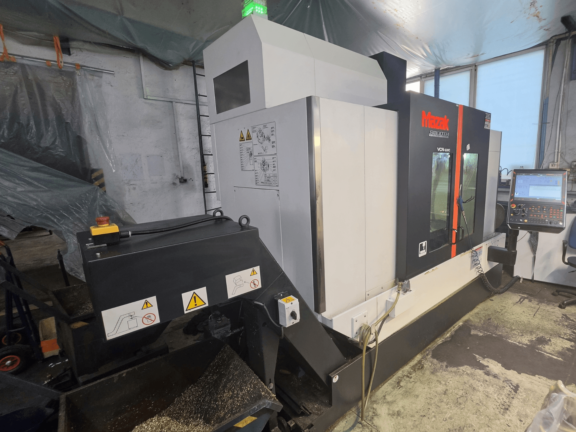 Vorderansicht des vertikalen Bearbeitungszentrums Mazak VCN-530C mit Bedienfeld, Werkzeugkette und Betriebsanzeigen.