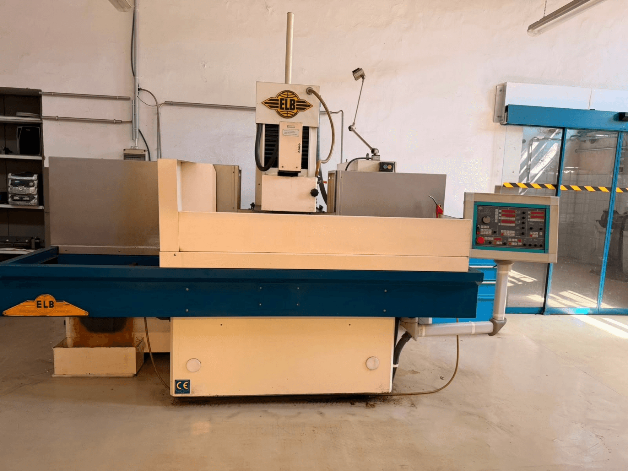 ELB Schliff Perfket 6 SPS-NK-Flachschleifmaschine, Vorderansicht mit Bedienfeld und blauem Sockel, in einer Werkstattumgebung.
