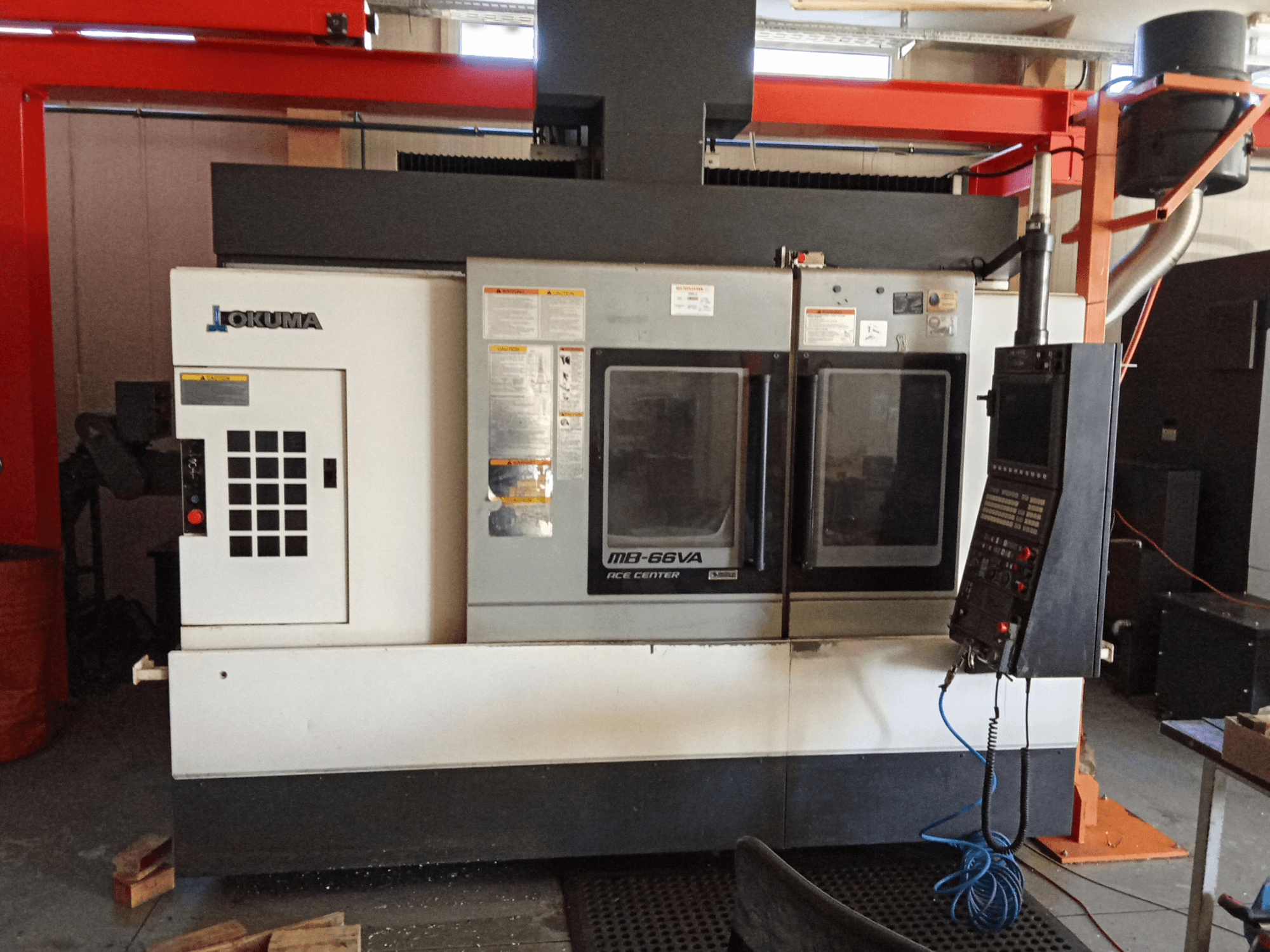 Vertikales Bearbeitungszentrum Okuma MB-66VA, Vorderansicht mit Bedienfeld und zwei Sichtfenstern für den Zugang zu den Werkzeugen.